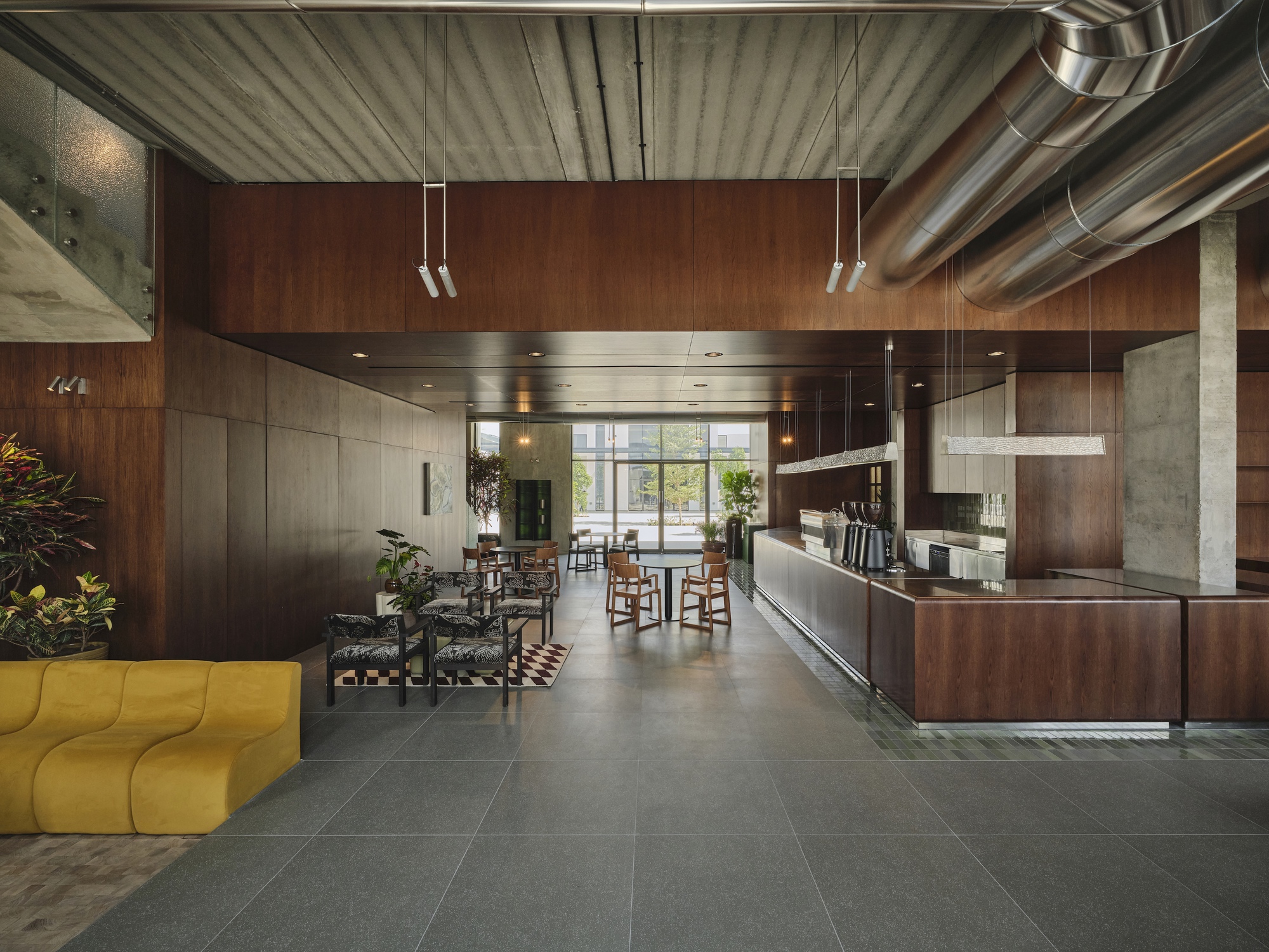 Long view through lobby showing suspended wood ceiling panels and reception desk beneath exposed ductwork