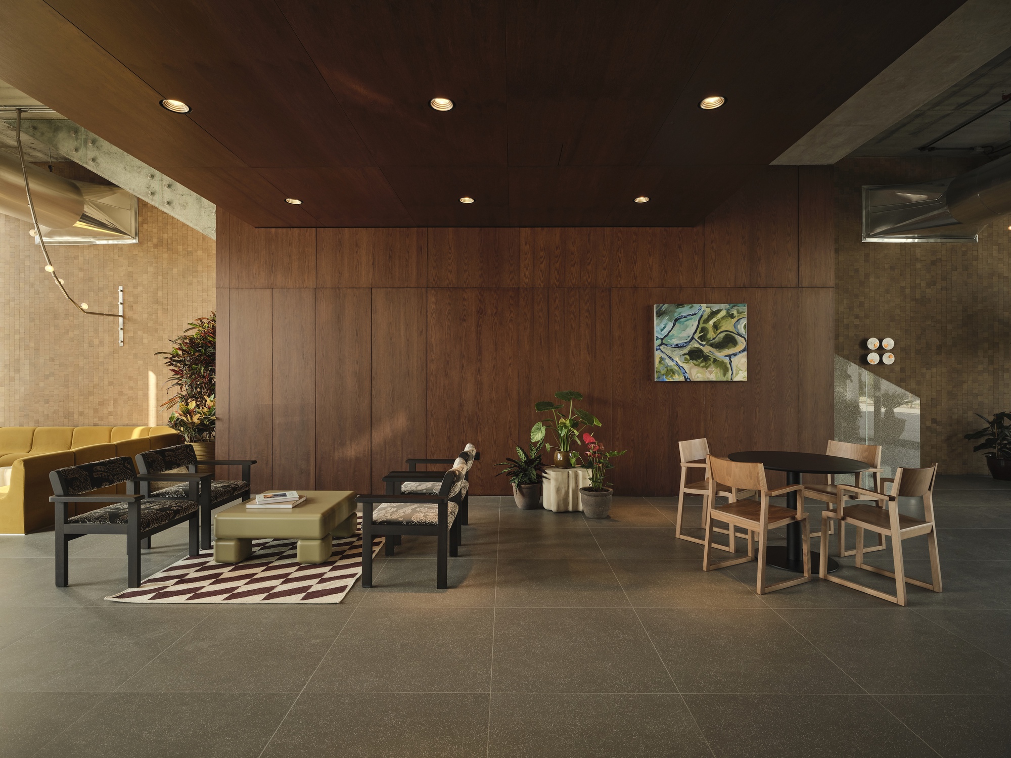 Seating area with walnut wall panels and concrete ceiling coffers illuminated by recessed downlights