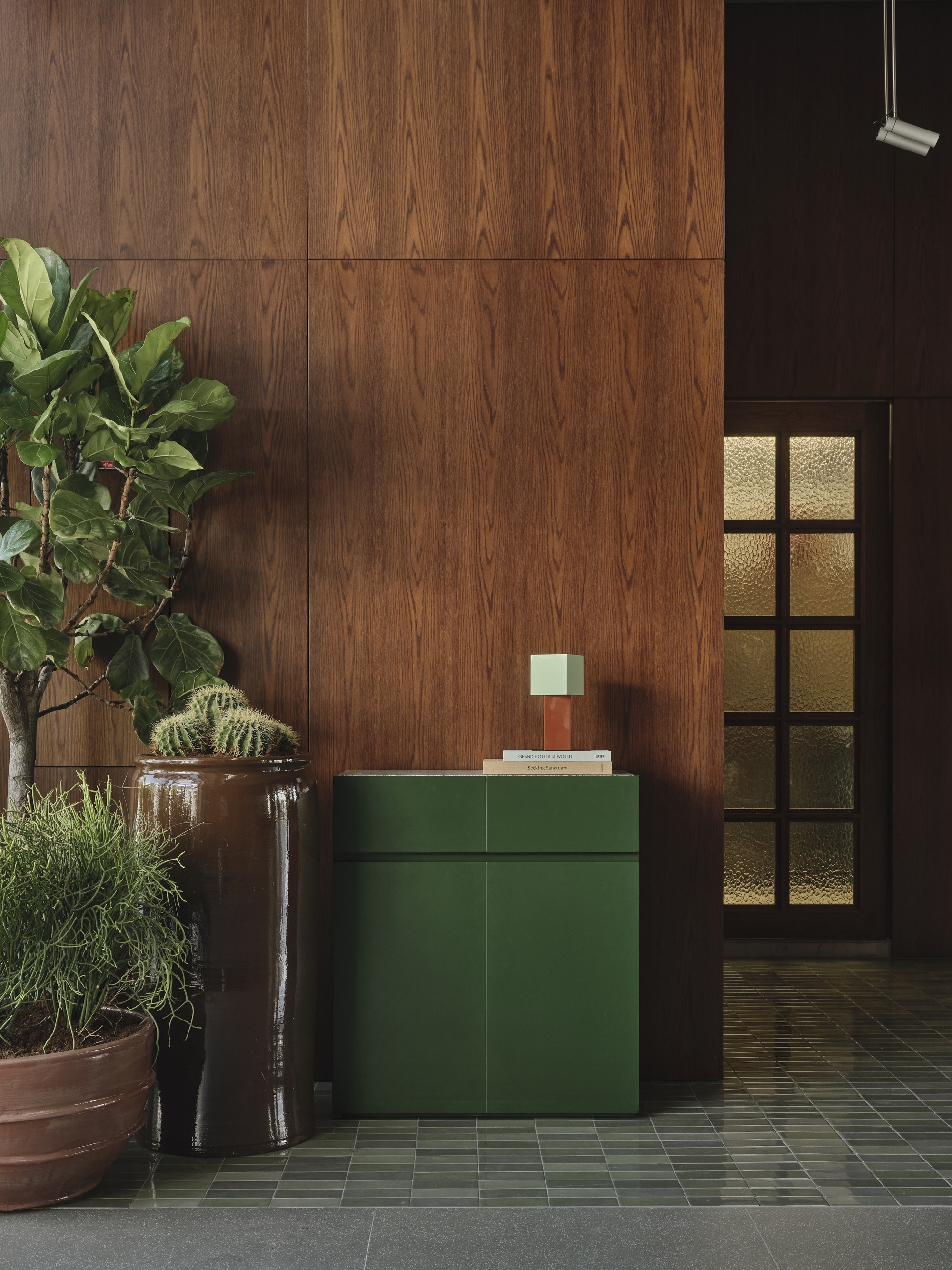 Green credenza beside potted plants and gridded glass door with warm light filtering through