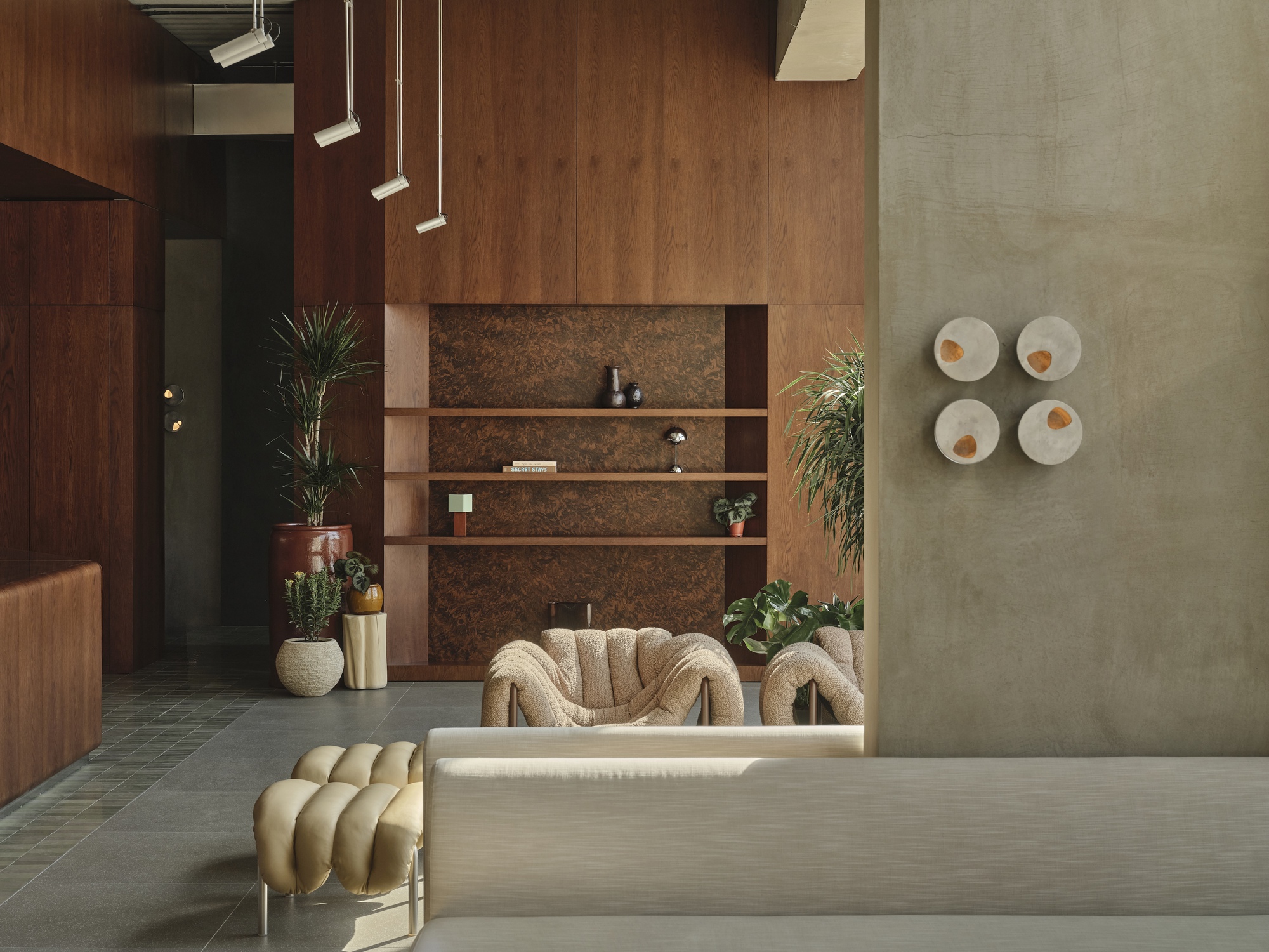 Reception lobby with cork-tiled accent wall and walnut wood paneling flanking a low desk and planter