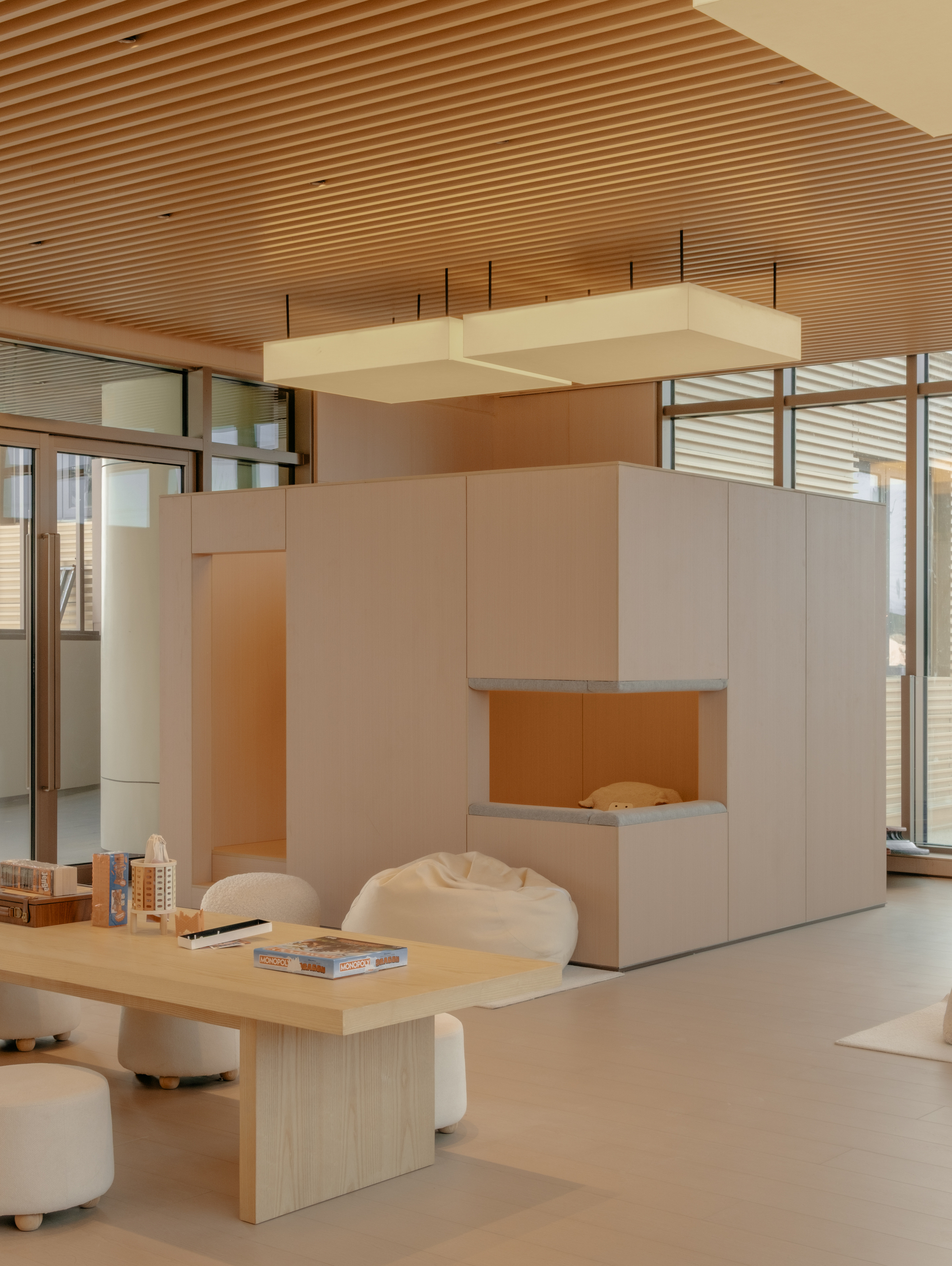 Reception pod with pale cabinetry and suspended ceiling element under a ribbed wooden soffit
