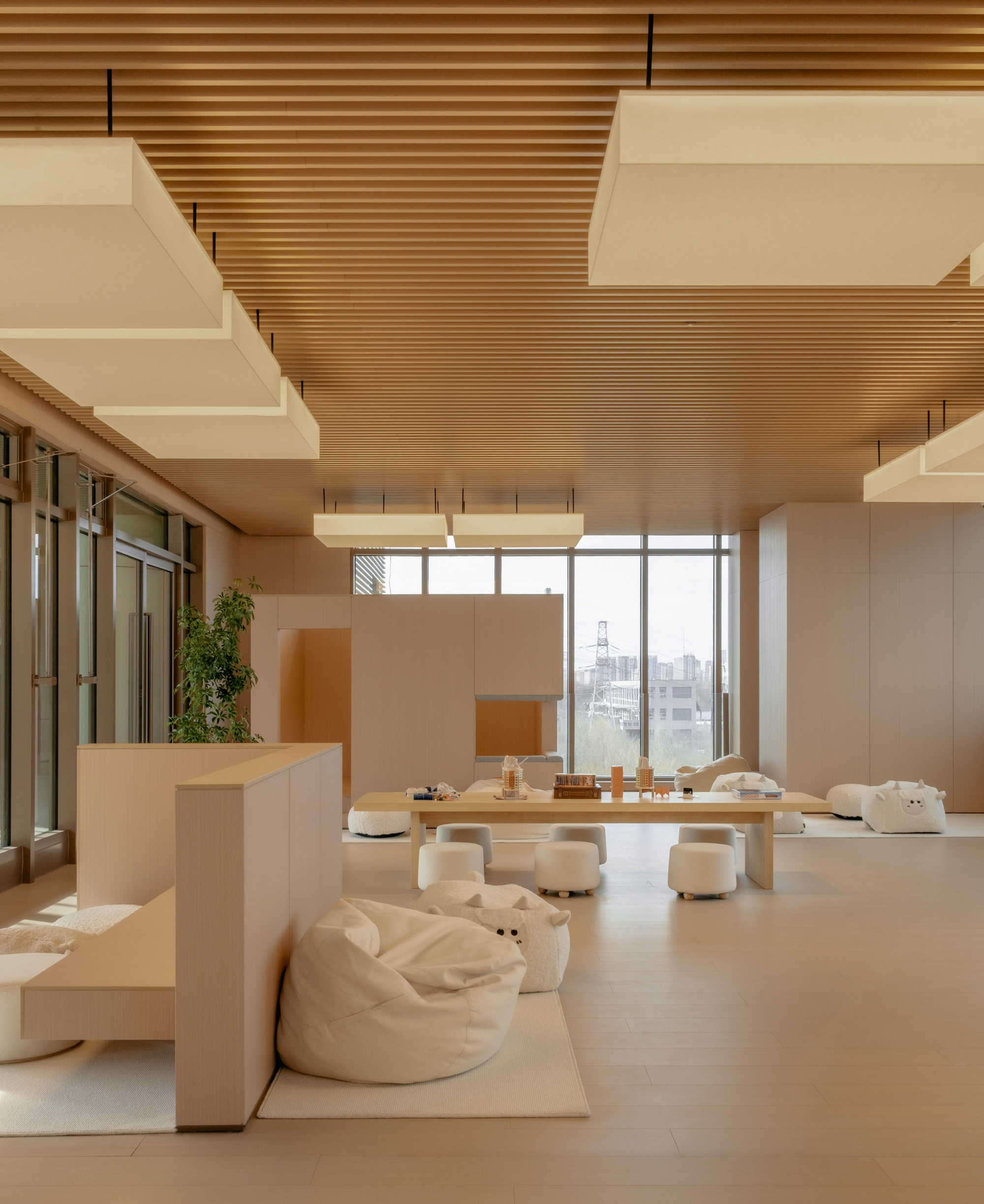 Lounge area with cream bean bag seating, freestanding planters, and cityscape visible through glazing
