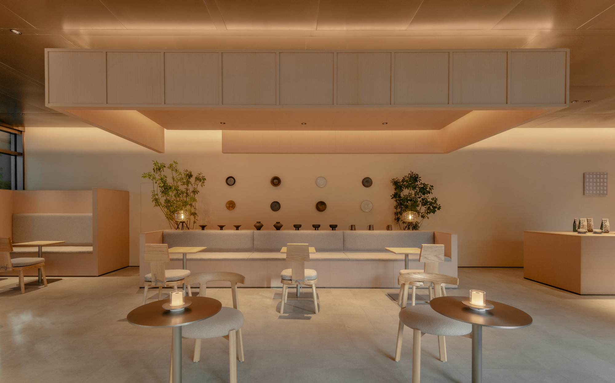 Recessed ceiling coffer above central counter with circular wall-mounted plates and flanking potted trees