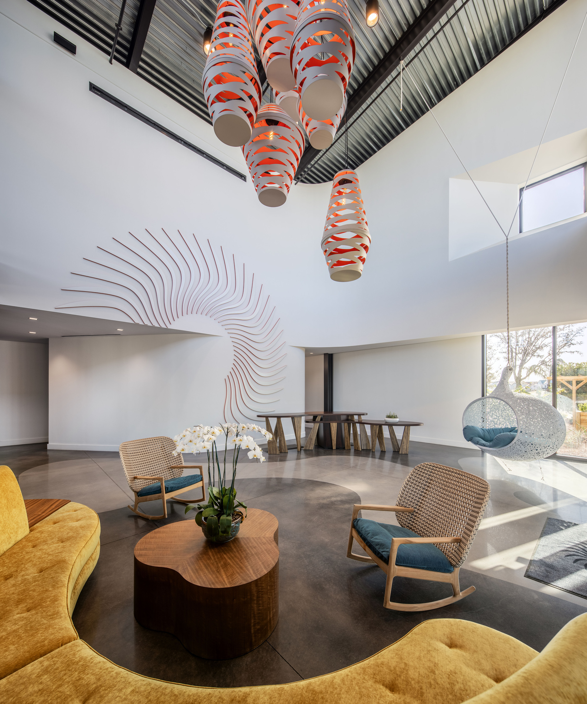 Double-height lobby with sculptural orange and white pendant lights hanging above a circular seating arrangement