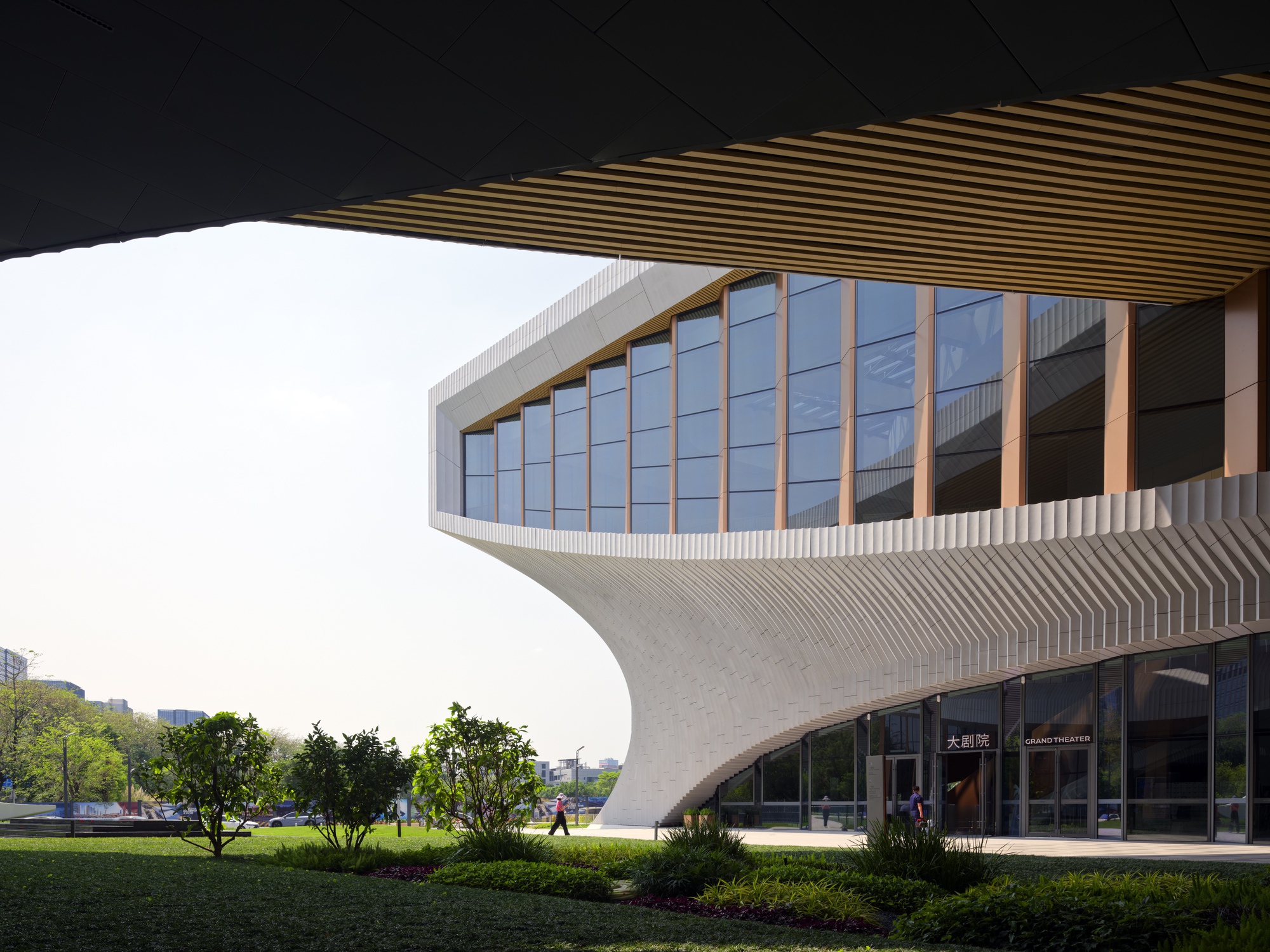 Cantilever volume with glazed curtain wall and timber mullions framed by ribbed soffit and white tile skin