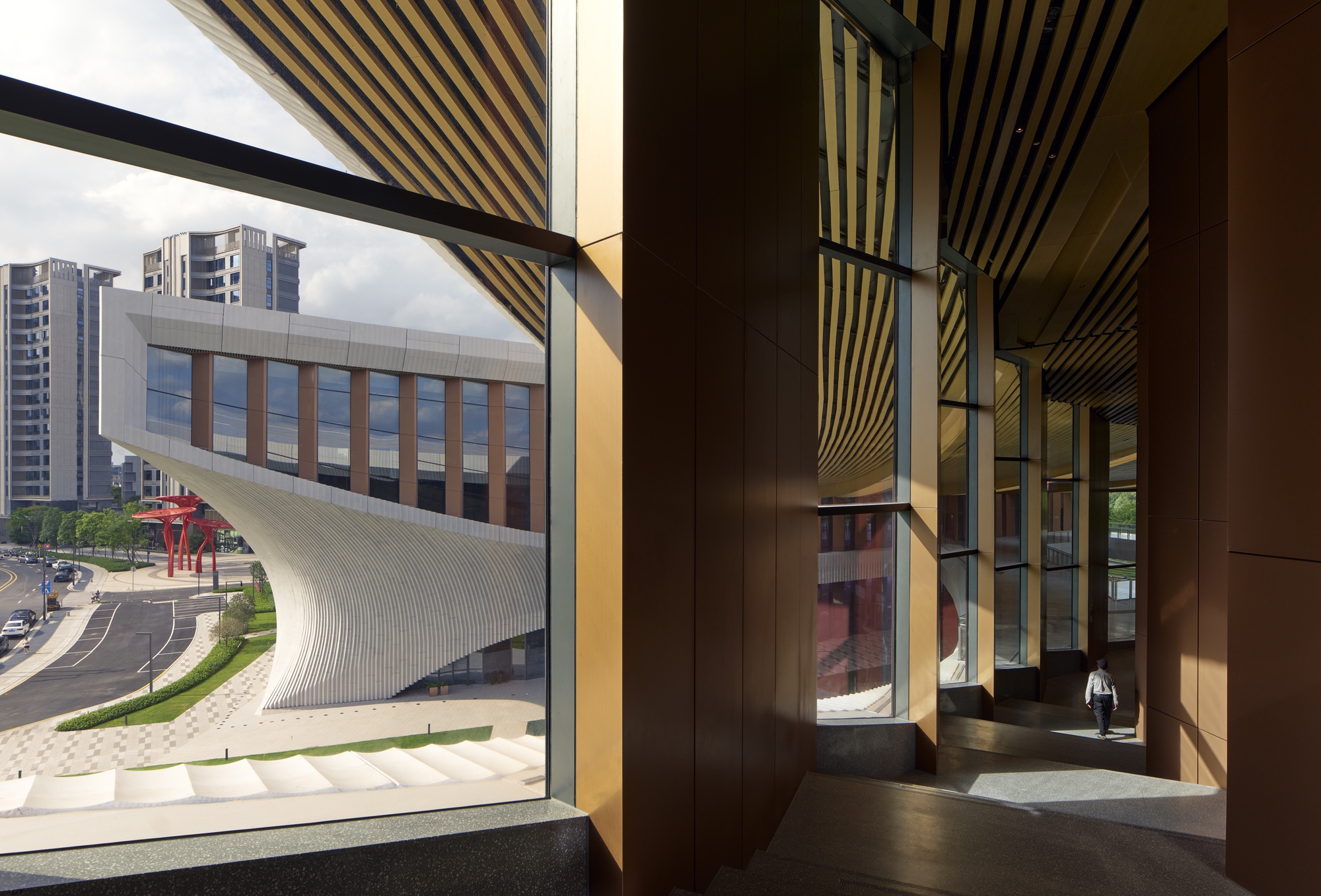 Interior hallway with striped timber ceiling and angled window framing a view of the curved facade