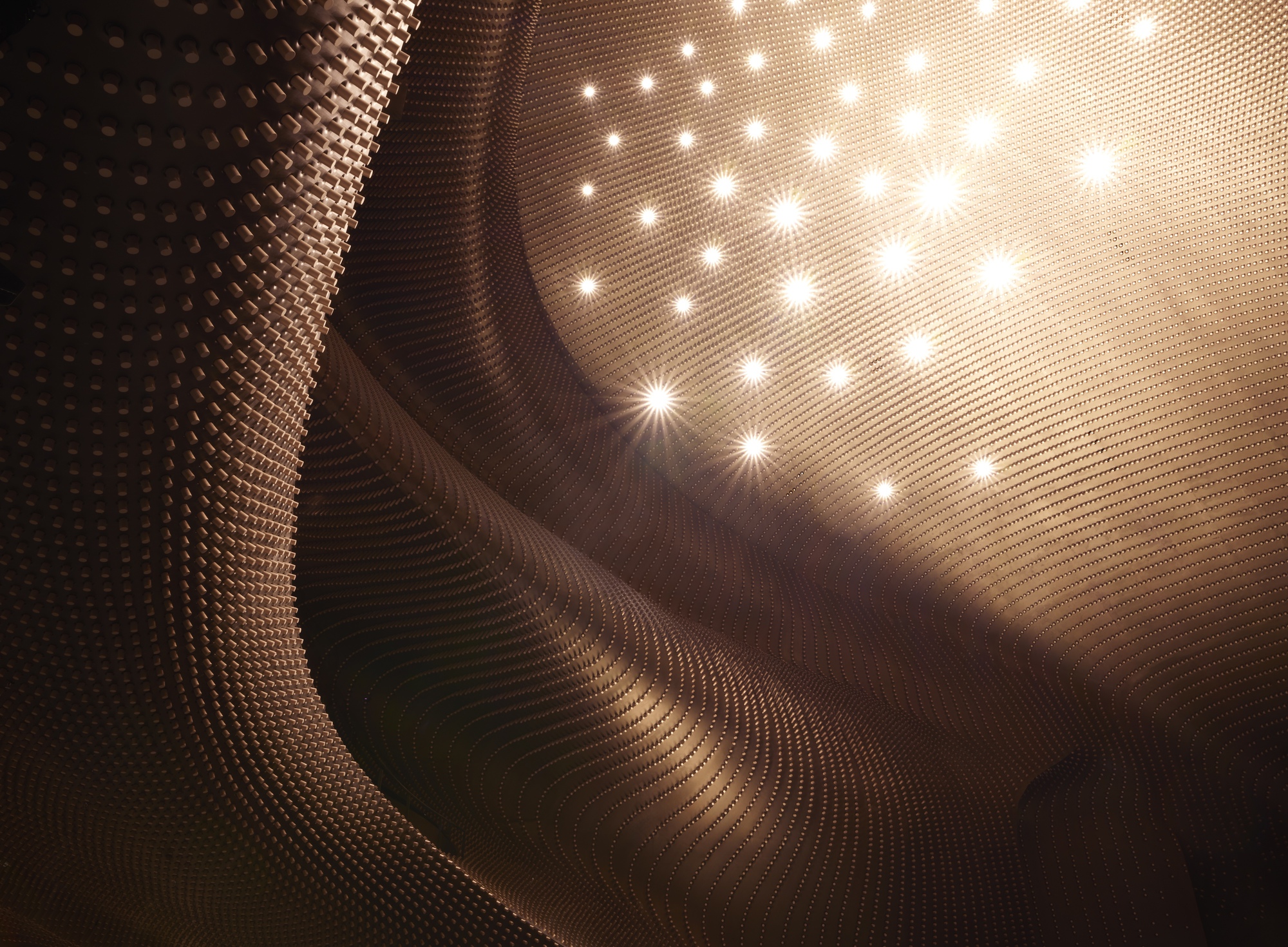 Close-up of the sculptural timber ceiling surface with embedded lighting creating starburst patterns