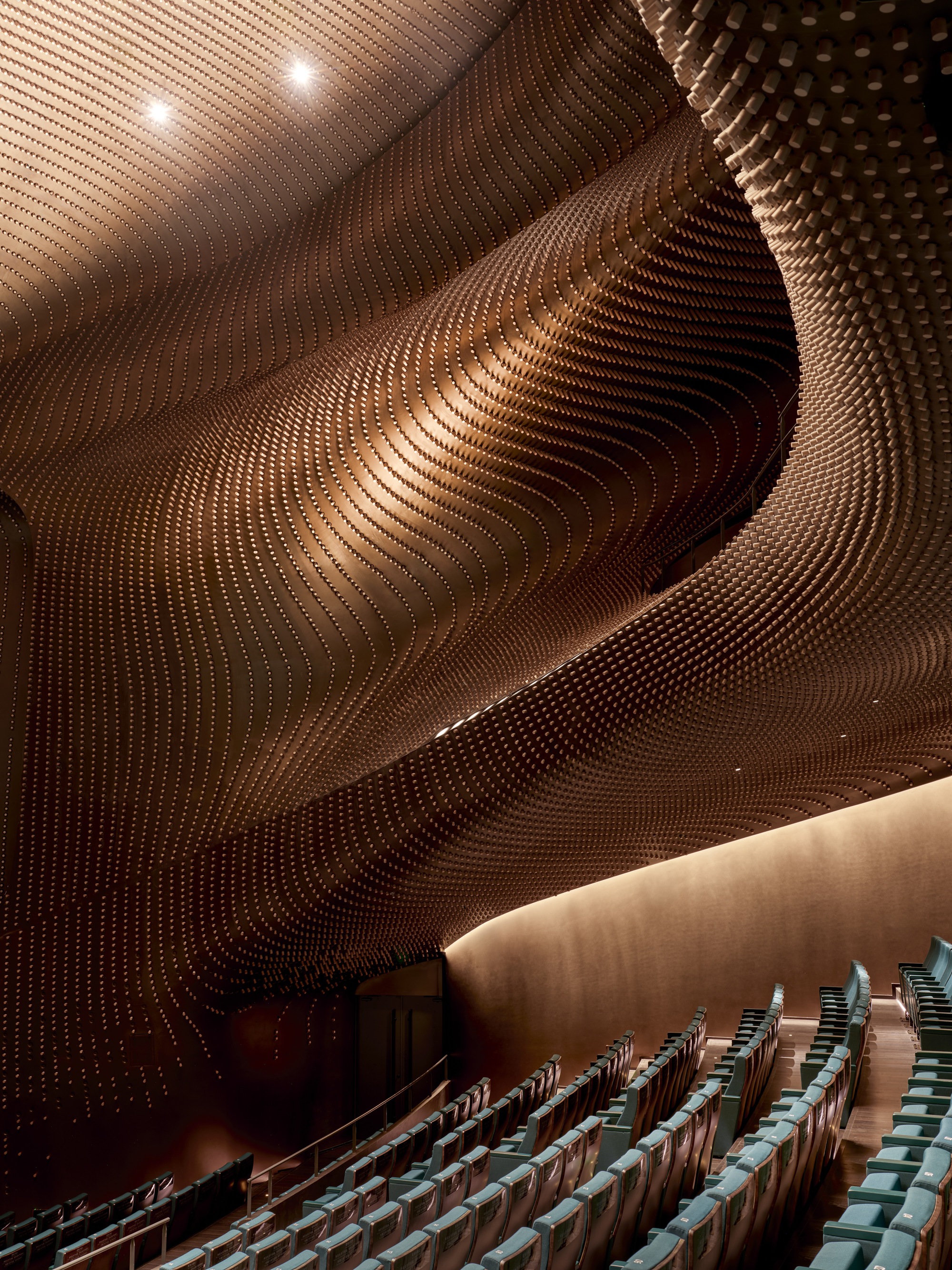 Upward view of the ribbed timber auditorium ceiling showing its wavelike folds and warm illumination