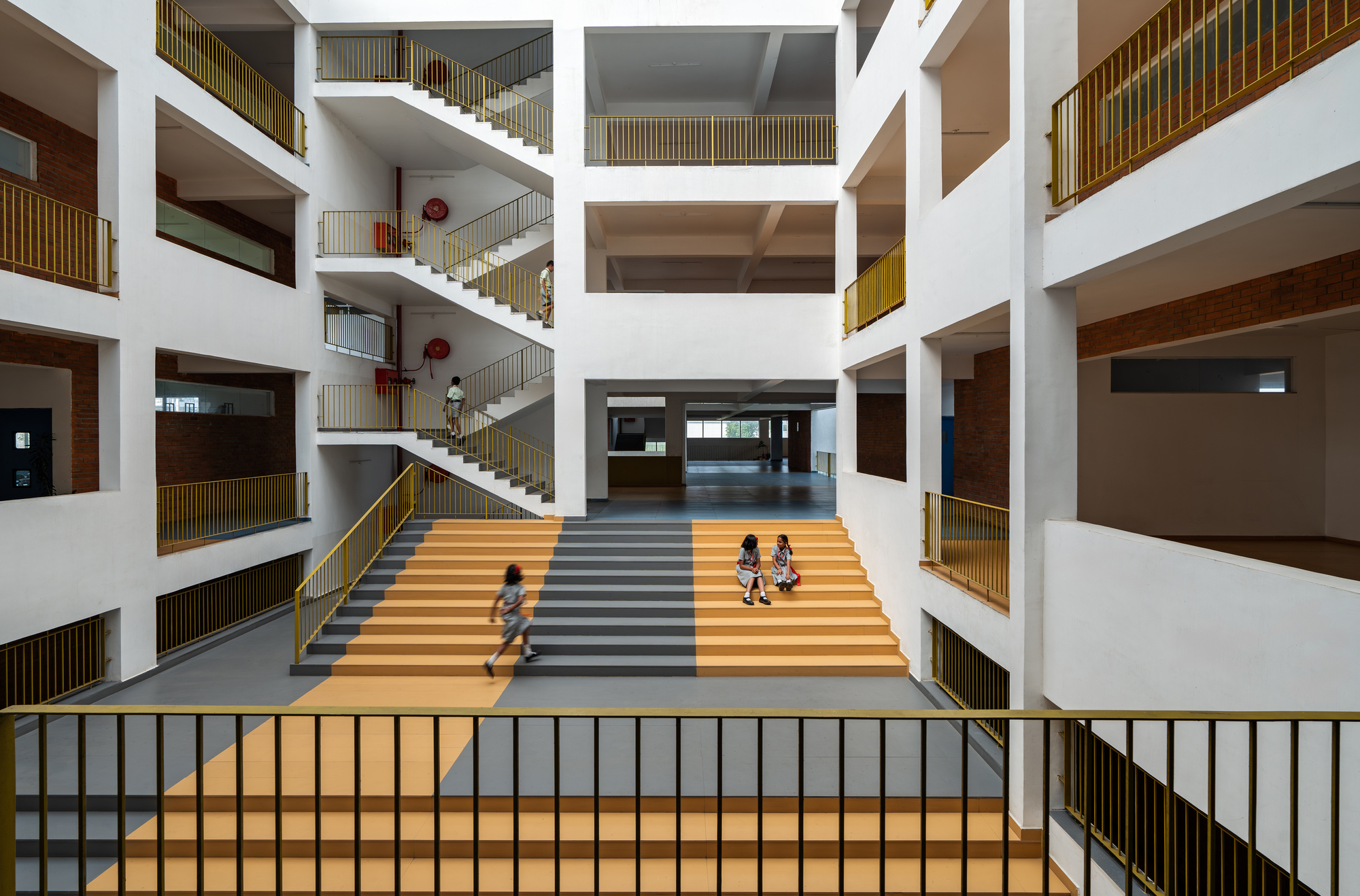 Central atrium with multi-story white balconies and striped stair where children play on the steps