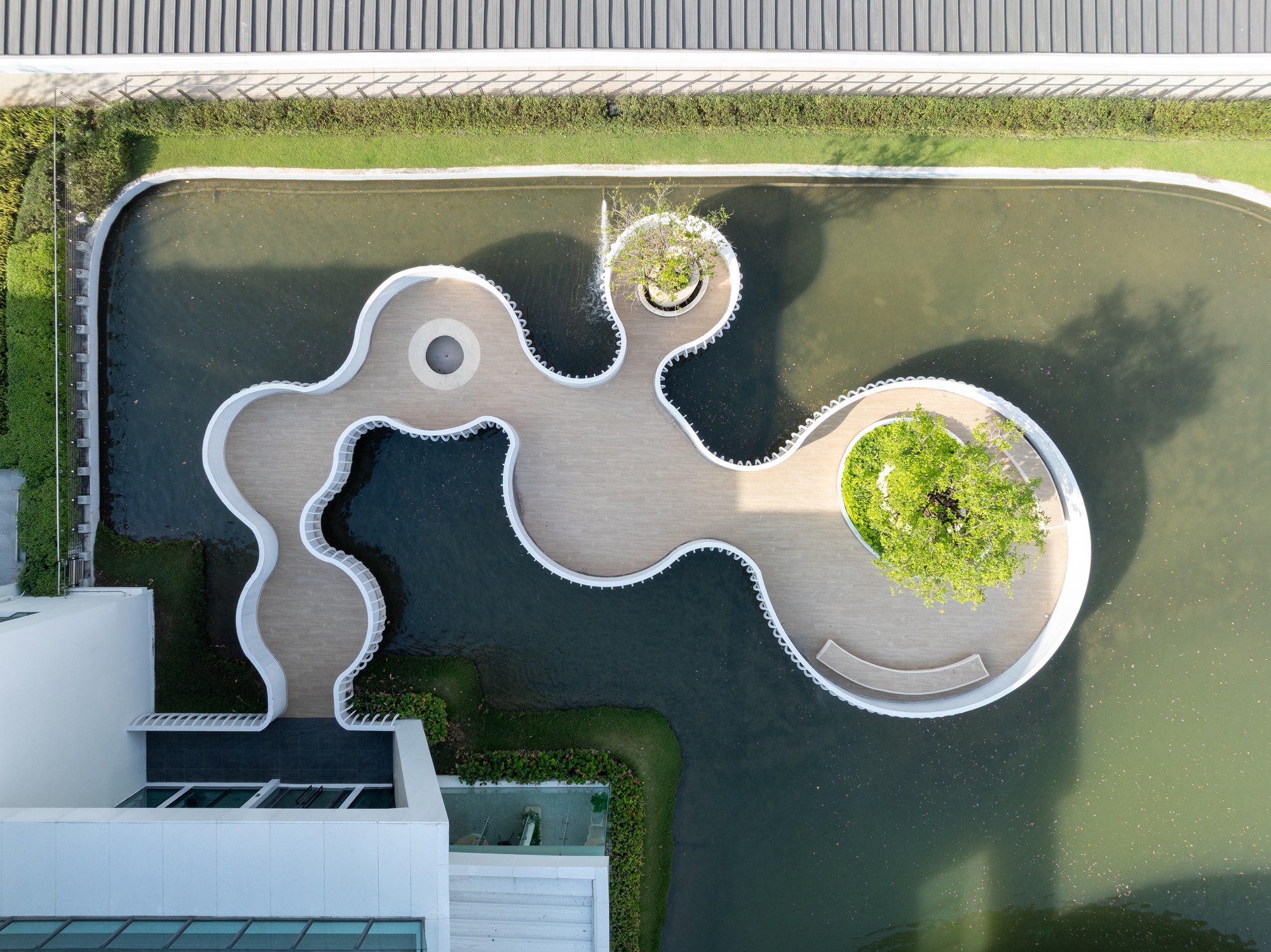 Aerial view of the sinuous white boardwalk deck winding through dark pond water with planted islands