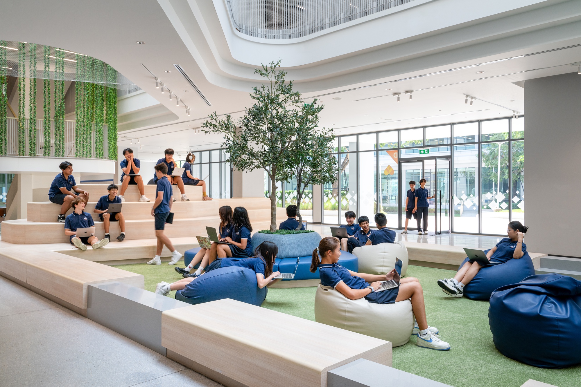 Terraced seating area with soft cushions and bean bags beneath a skylighted ceiling with indoor tree