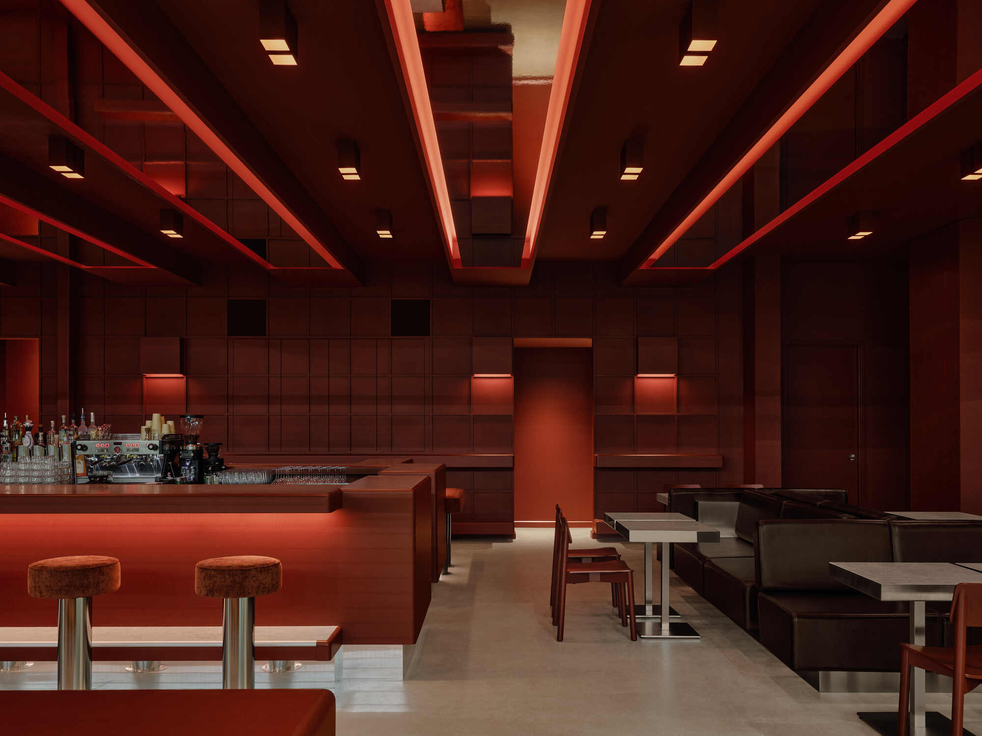 Lounge area with coffered ceiling, backlit bar counter, and dark leather seating beneath linear light strips