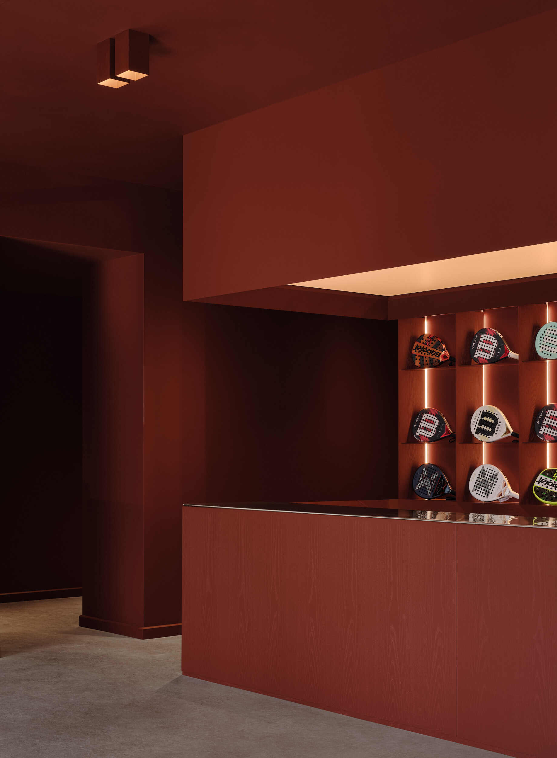 Display niche with backlit shelves holding merchandise beneath a floating illuminated soffit in terracotta tones