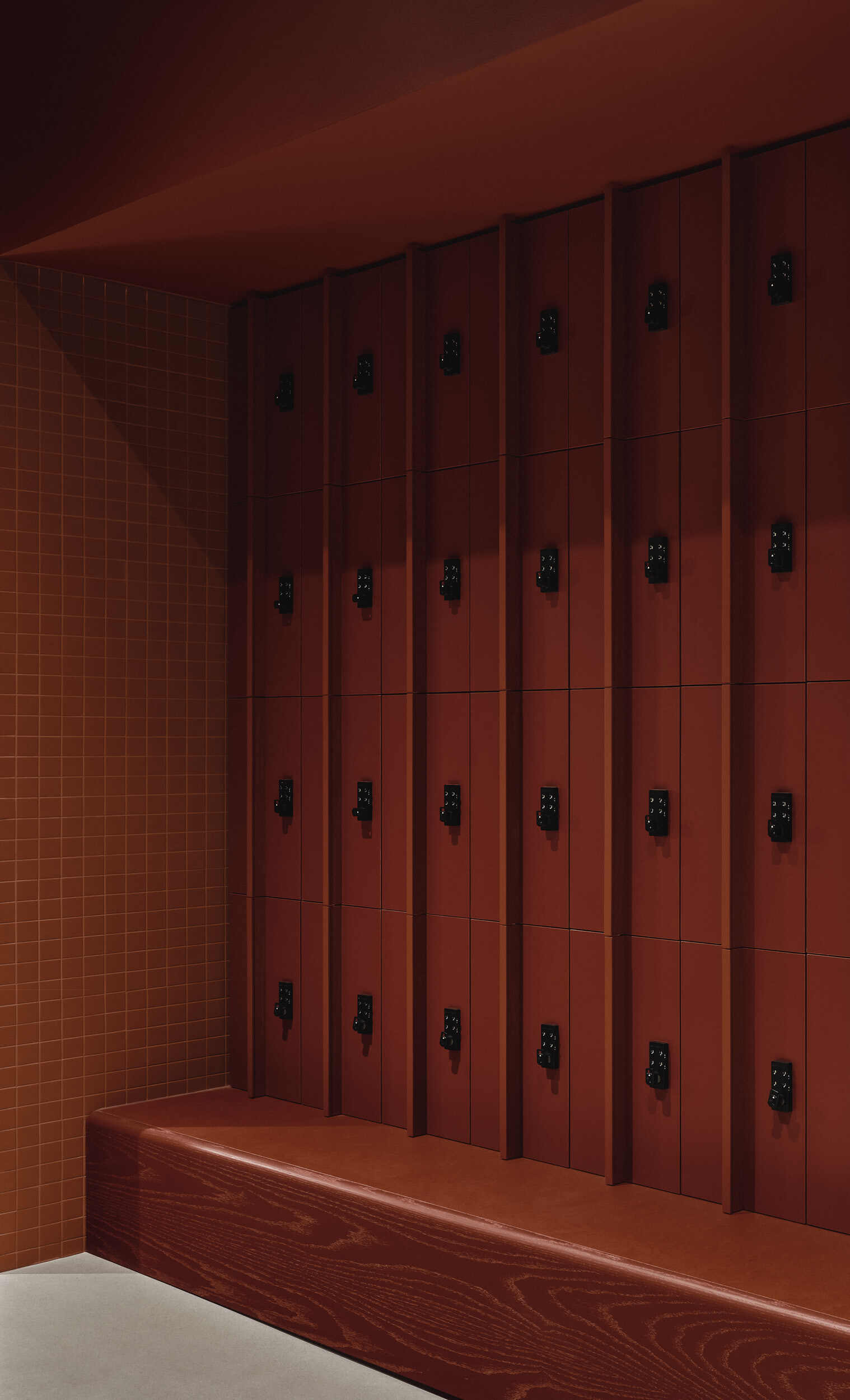 Wood locker wall with black metal latches above a bench beside a tile wall