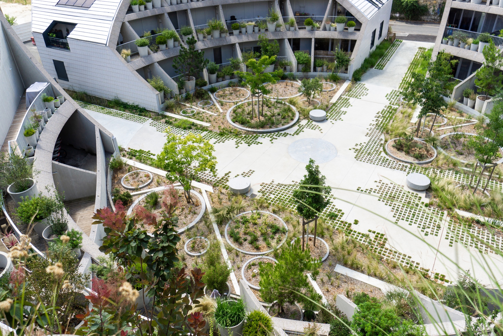 Aerial view of a central courtyard with circular planted beds and perforated paving surrounded by residential balconies