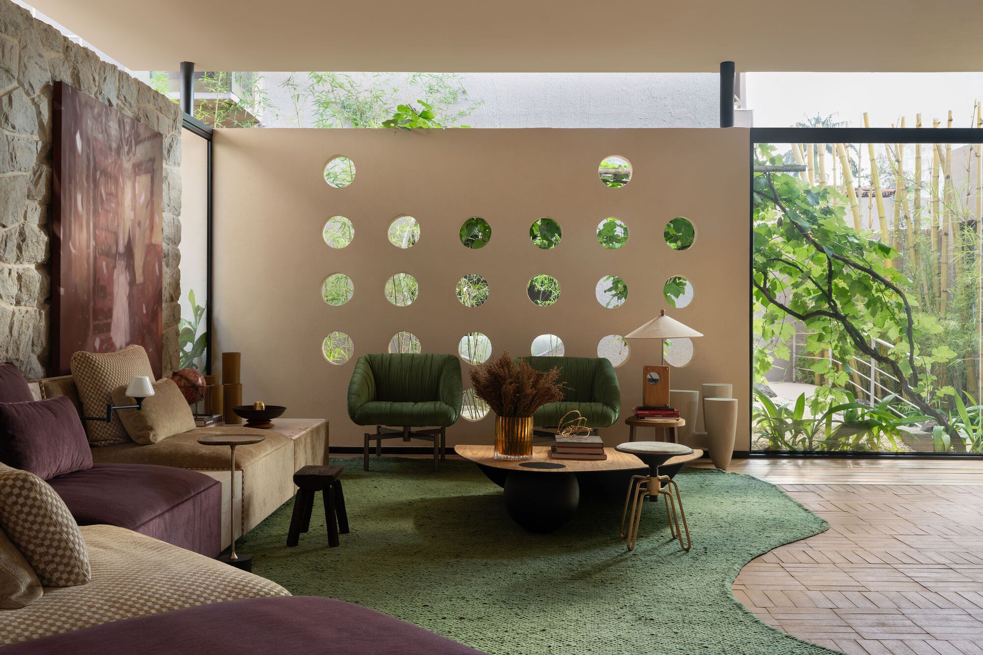 Living room with circular openings in the beige partition wall framing views to the garden beyond