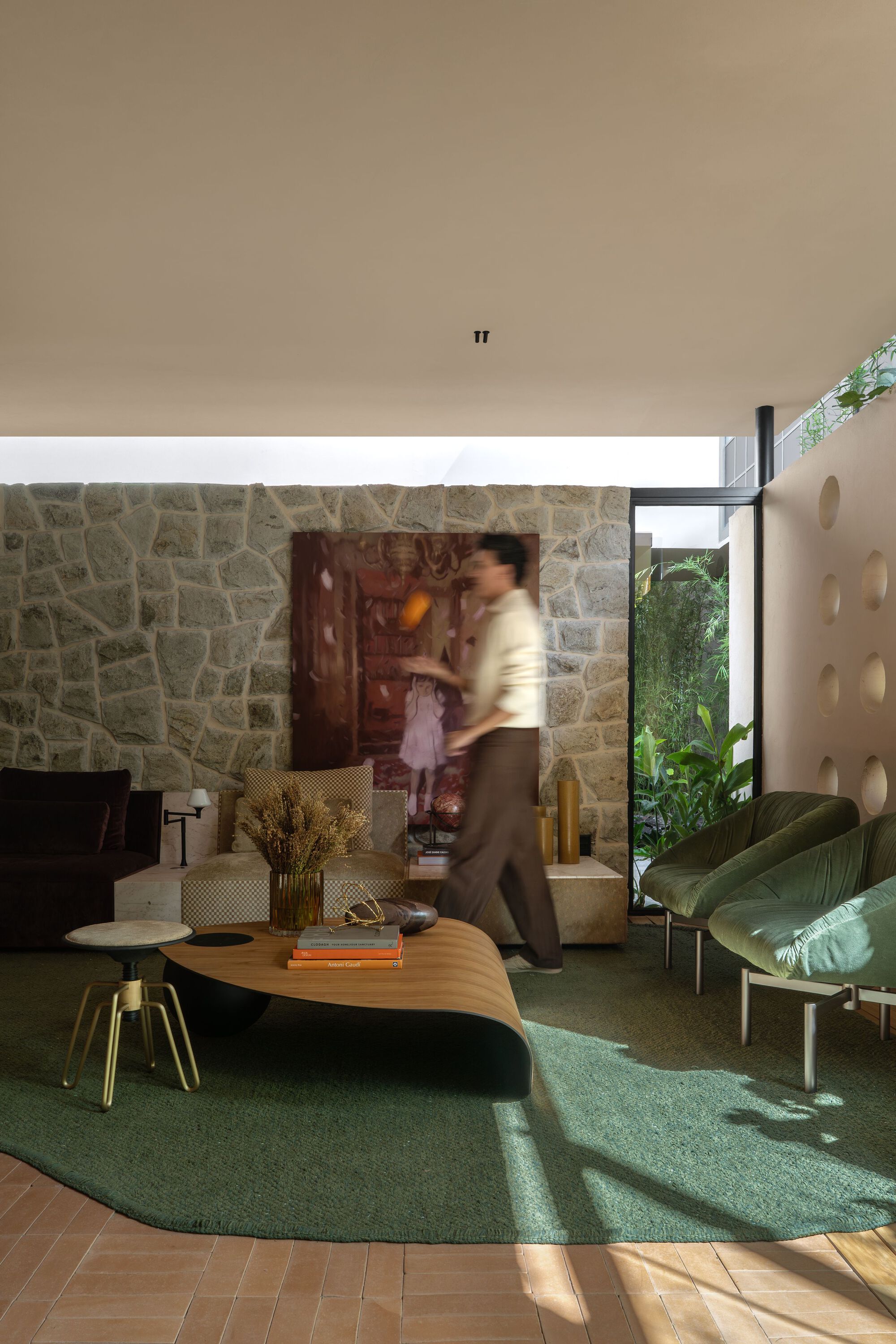 Person walking through the living space with green rug and organic-shaped coffee table
