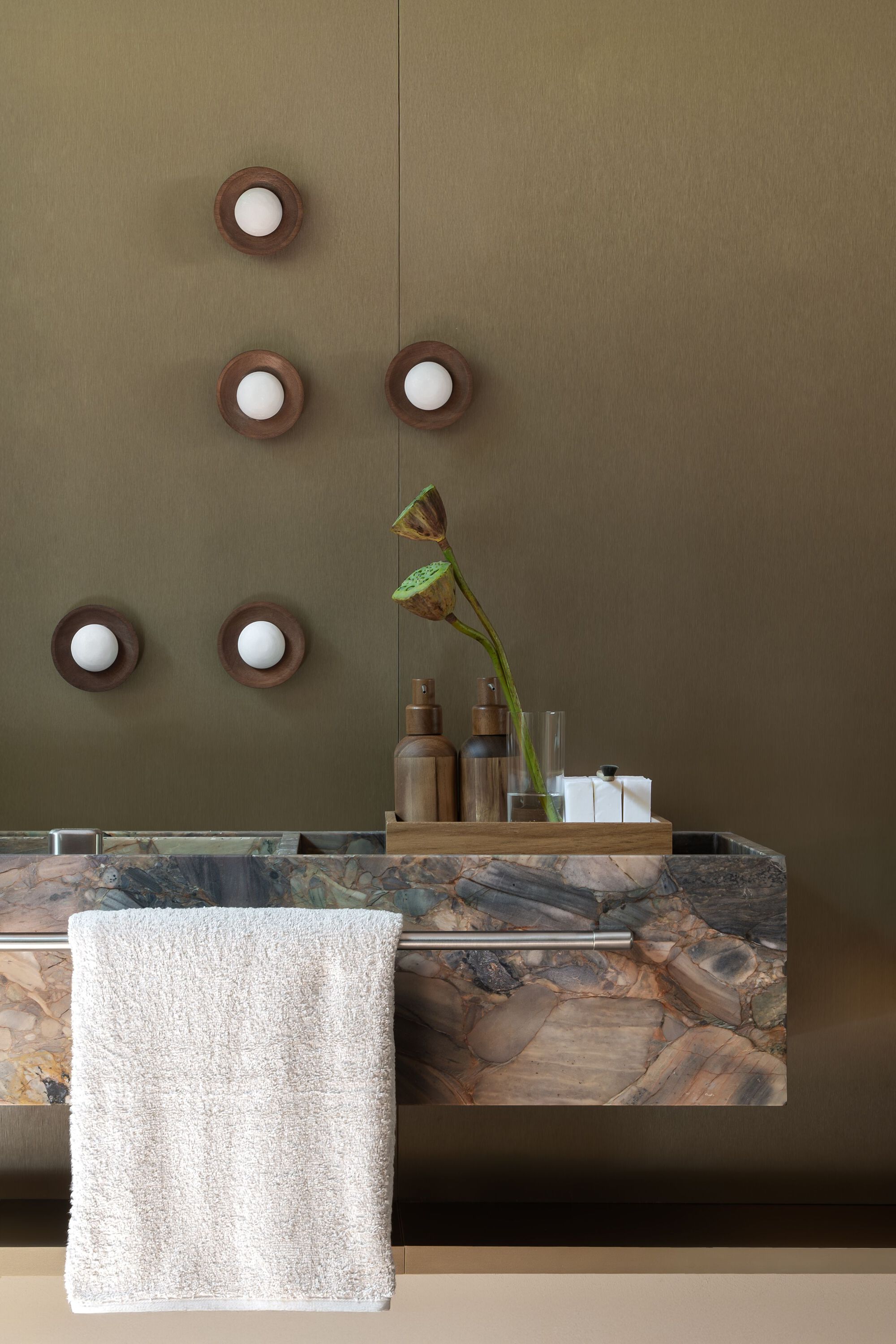 Marble vanity with live-edge timber detail and circular wall sconces on an olive-toned wall