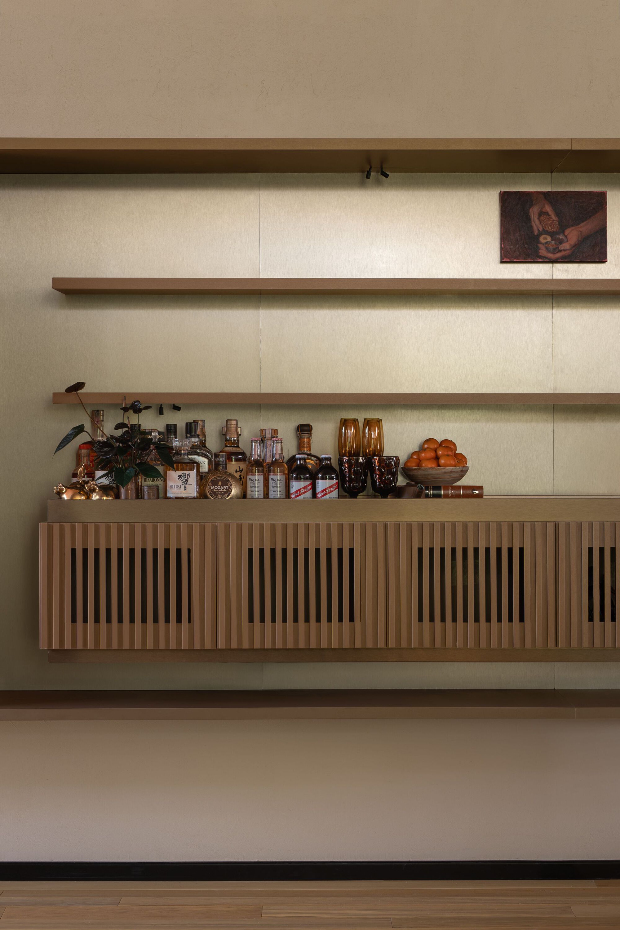 Built-in credenza with vertical slat panels and timber shelves displaying bottles and objects