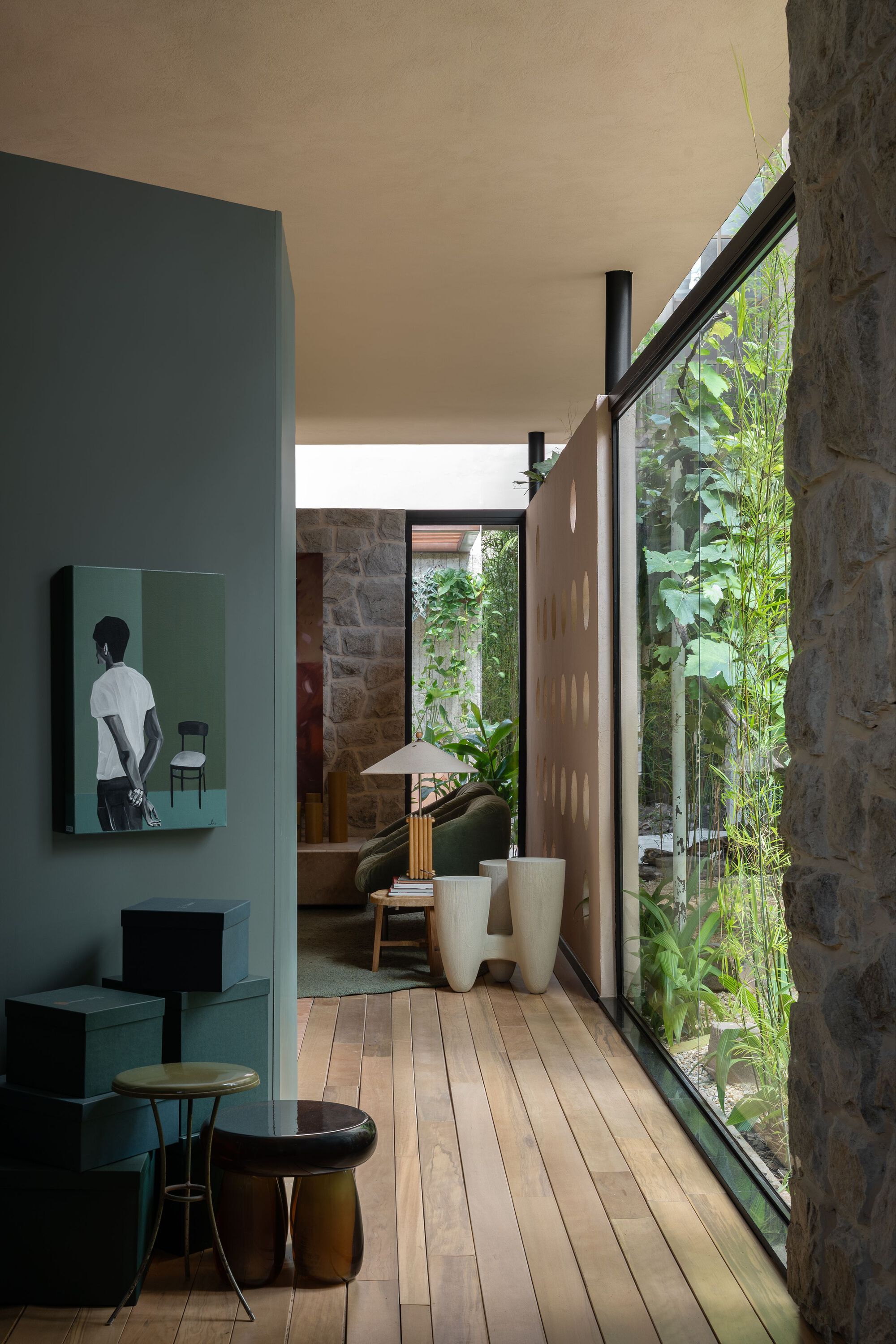 Floor-to-ceiling glazing overlooking a planted courtyard with exposed stone walls and bamboo