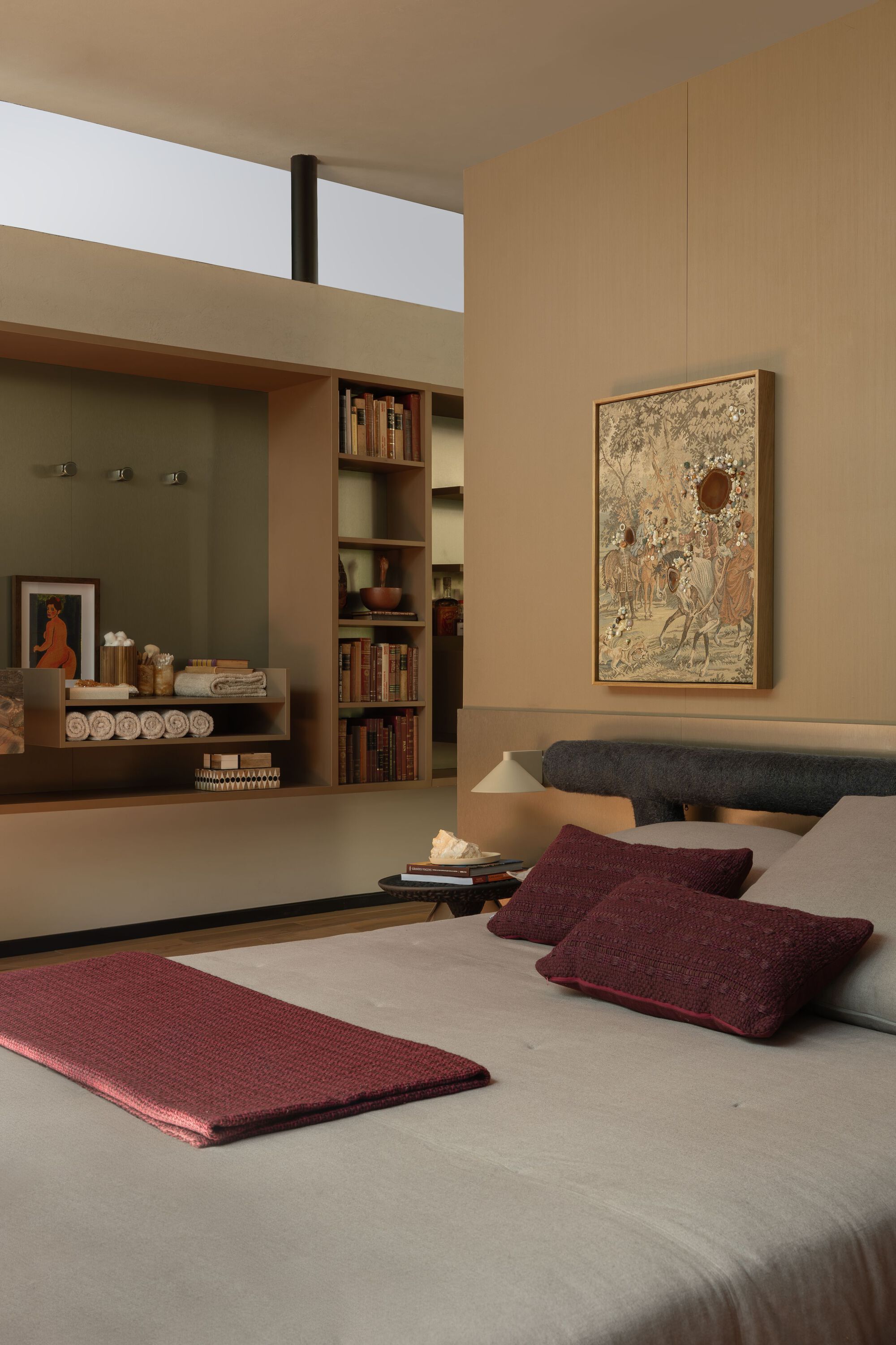 Bedroom with built-in shelving and clerestory window above in warm afternoon light