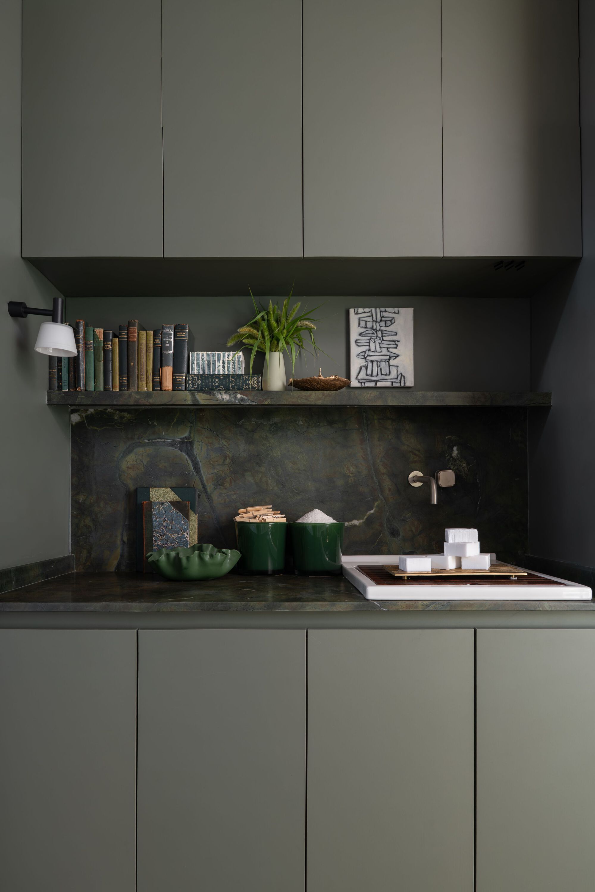 Kitchen nook with dark stone backsplash and floating shelf beneath grey upper cabinets