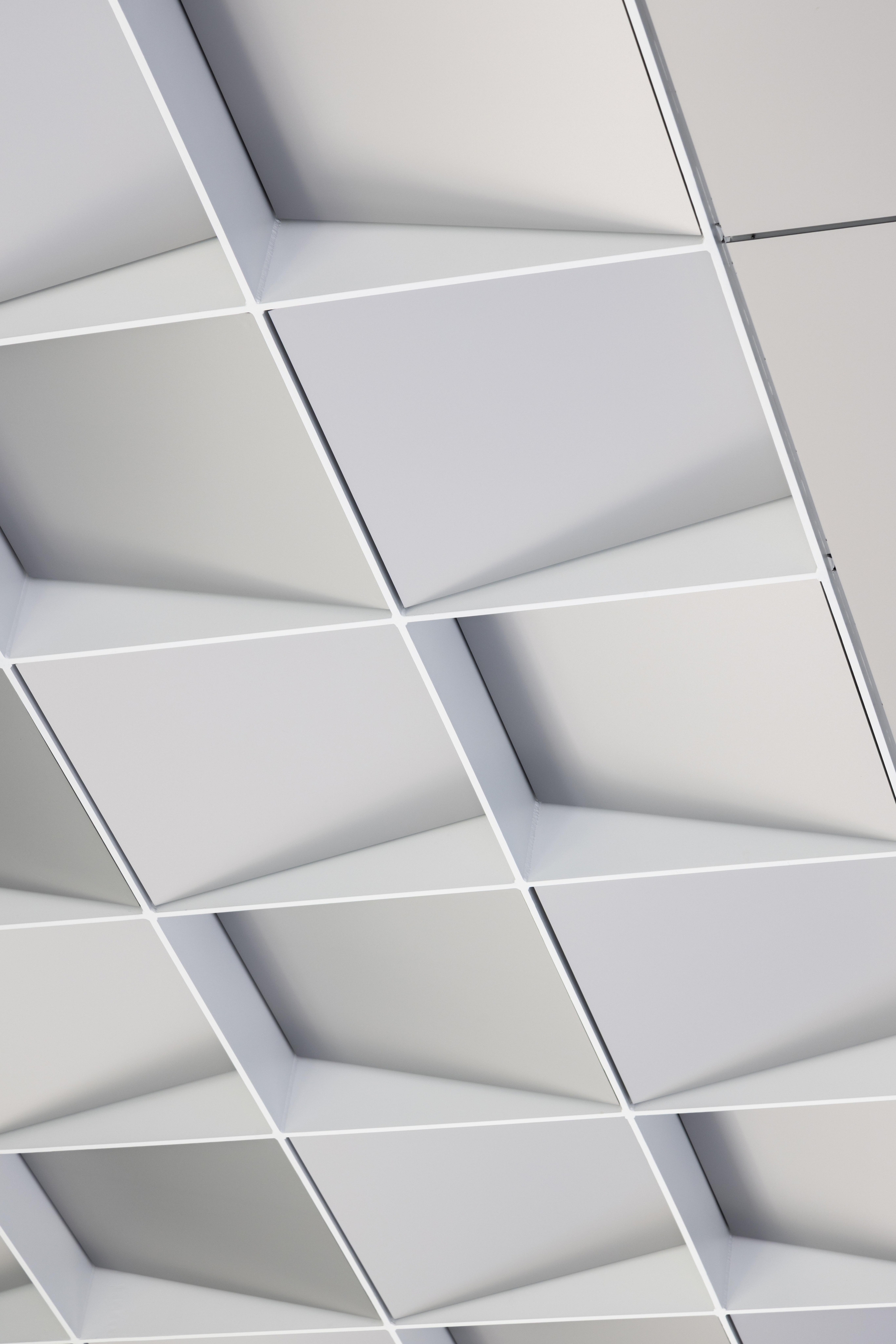 Close-up of white geometric coffered ceiling panels with recessed joints and shadows