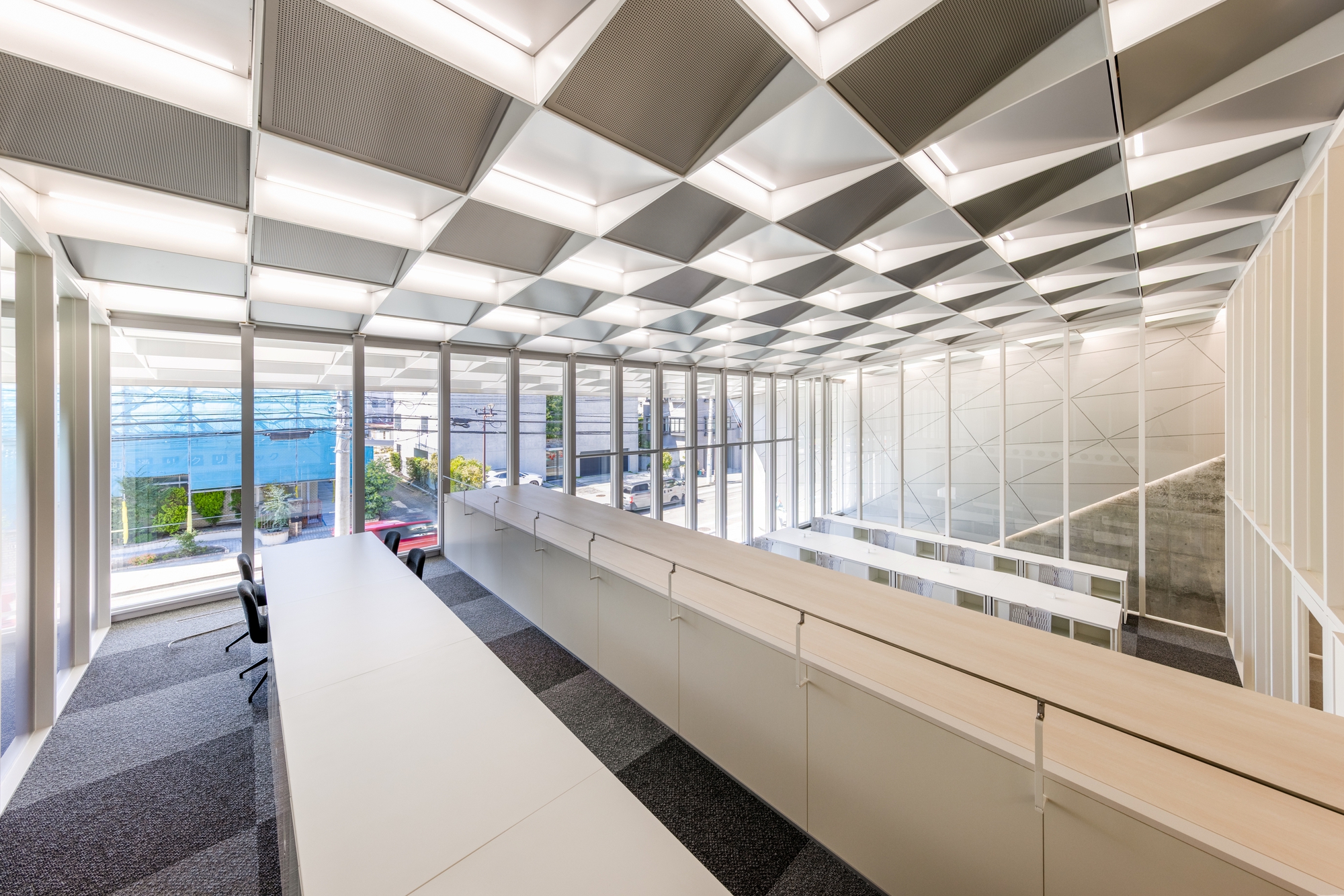Office interior with low partition workstations under a coffered ceiling looking toward glazed courtyard entry