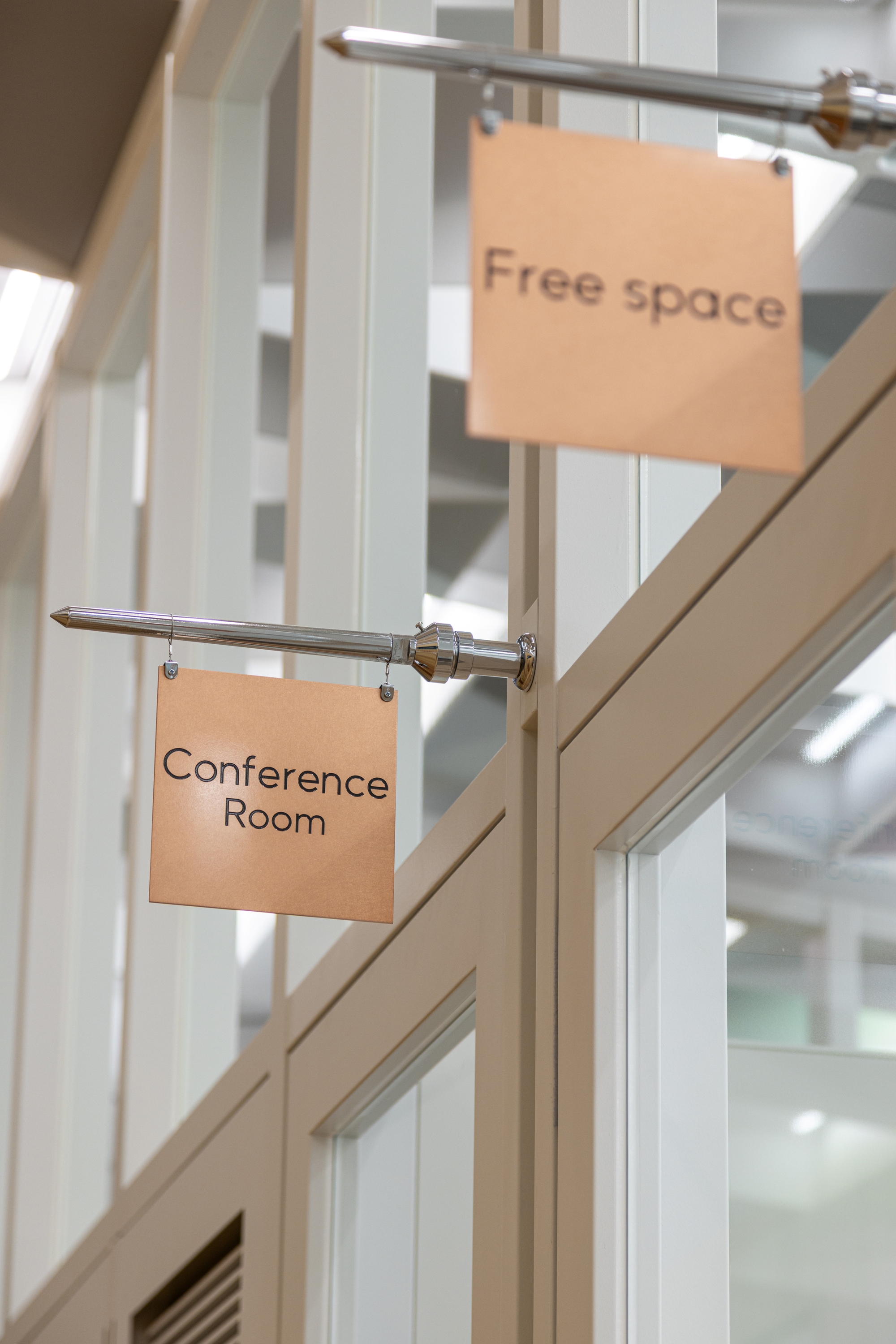 Hung signage panels on metal rod brackets mounted between white painted timber wall panels
