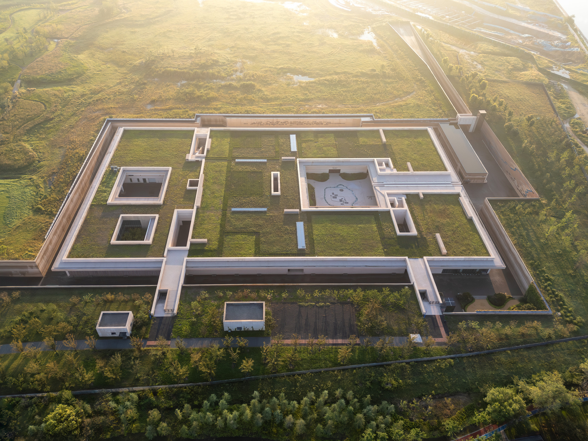 Aerial view of the rectangular compound with grass-covered rooftops and courtyards in morning mist