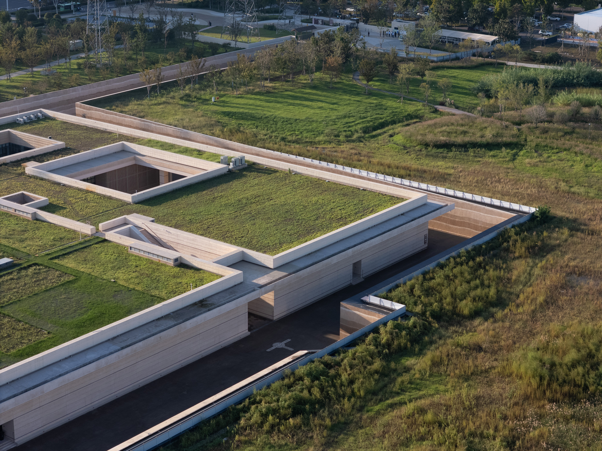 Drone view of the terraced volumes with planted roofs and courtyards surrounded by landscape and parkland