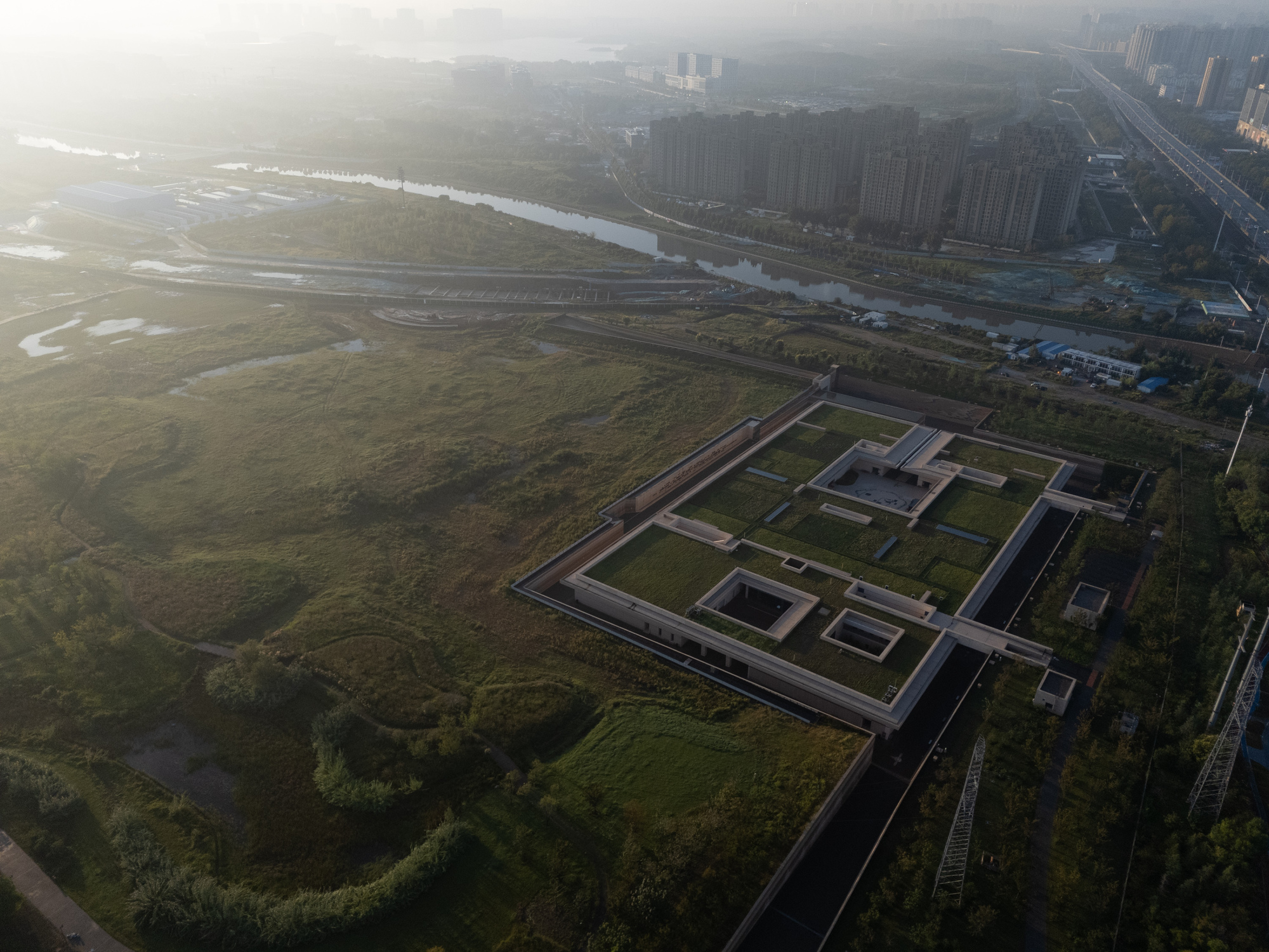 Aerial perspective of the walled compound with rectangular courtyards and low rooflines in hazy morning light