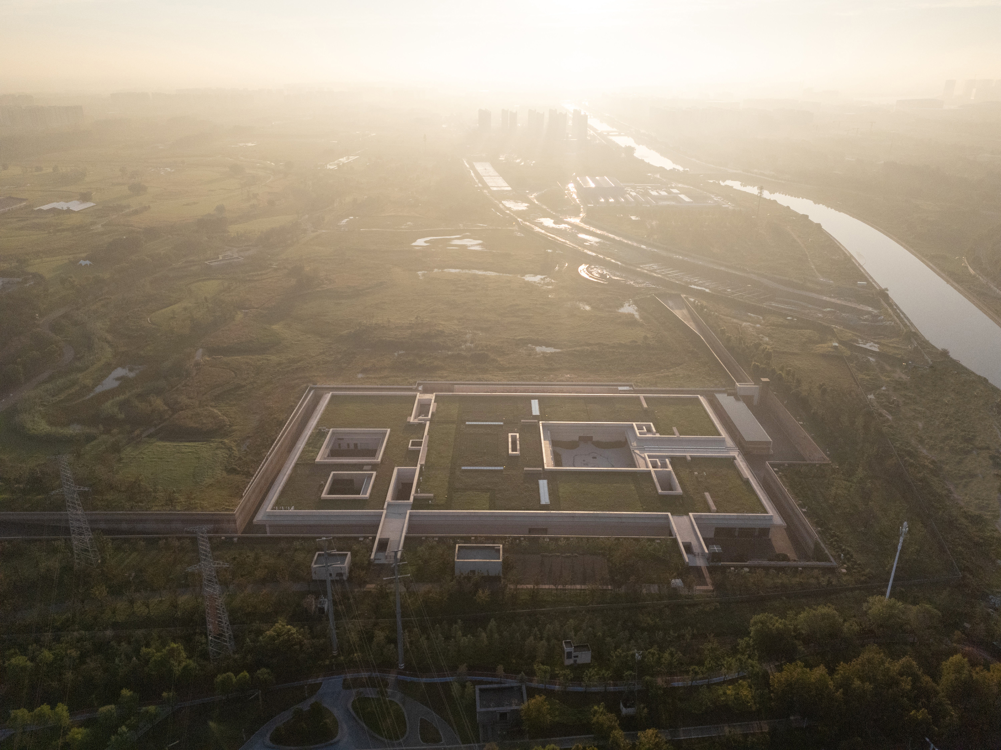 Drone view of the rectilinear roof composition surrounded by wetlands in morning haze
