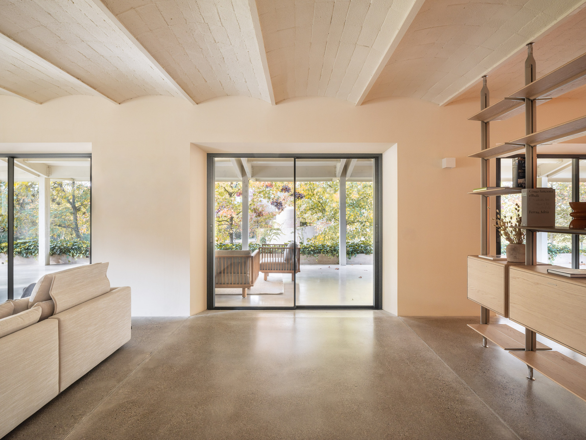 Living room with exposed timber ceiling beams and sliding glass doors opening to a terrace