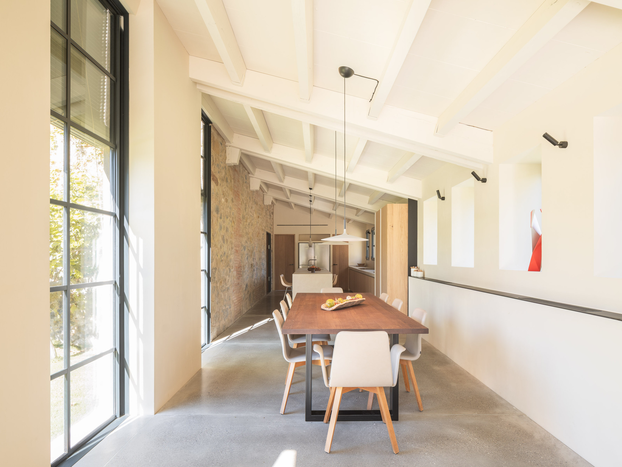 Dining area with tall steel-framed windows and exposed timber ceiling joists spanning the length