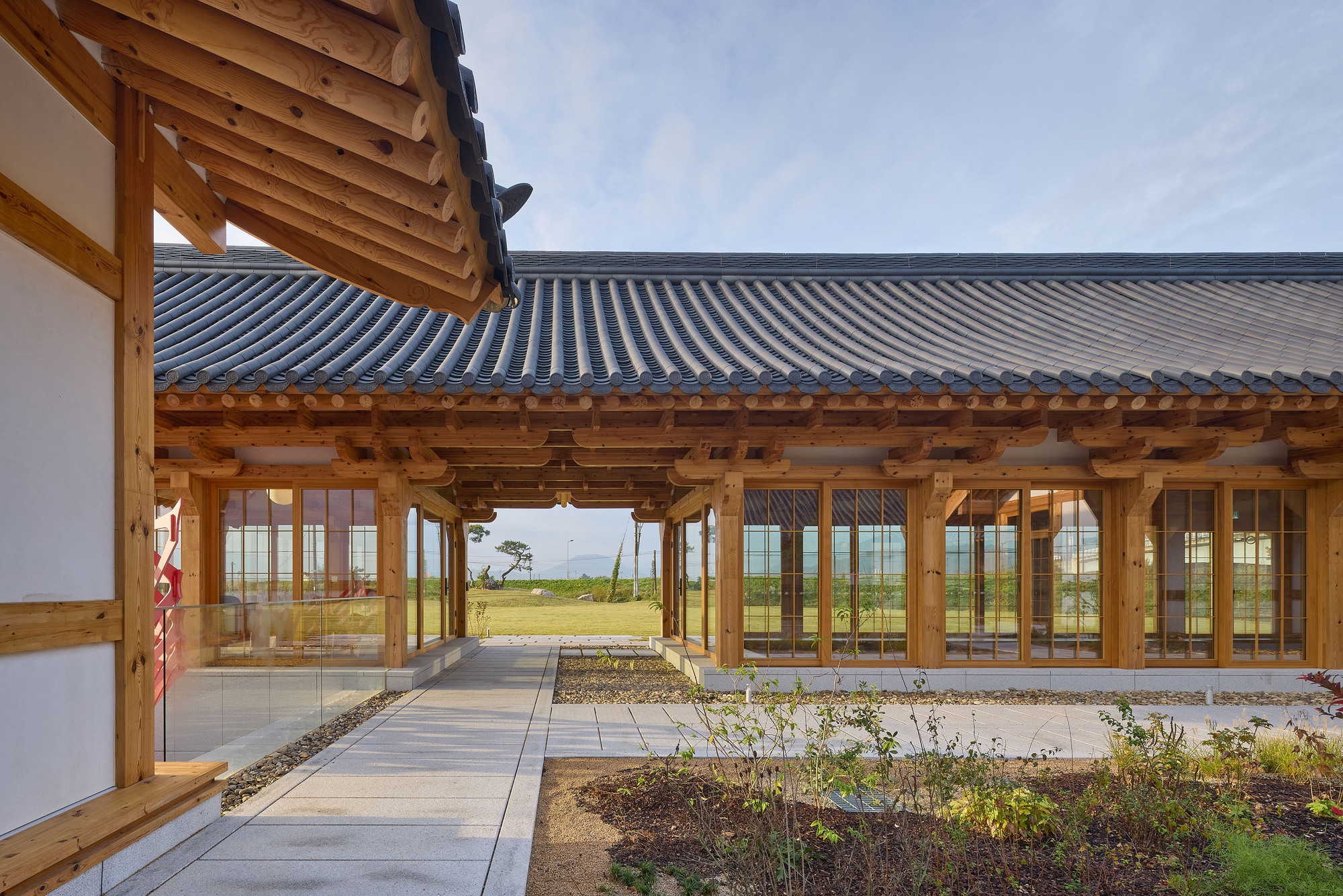 Covered courtyard walkway with timber columns and glazed doors opening to a planted garden beyond