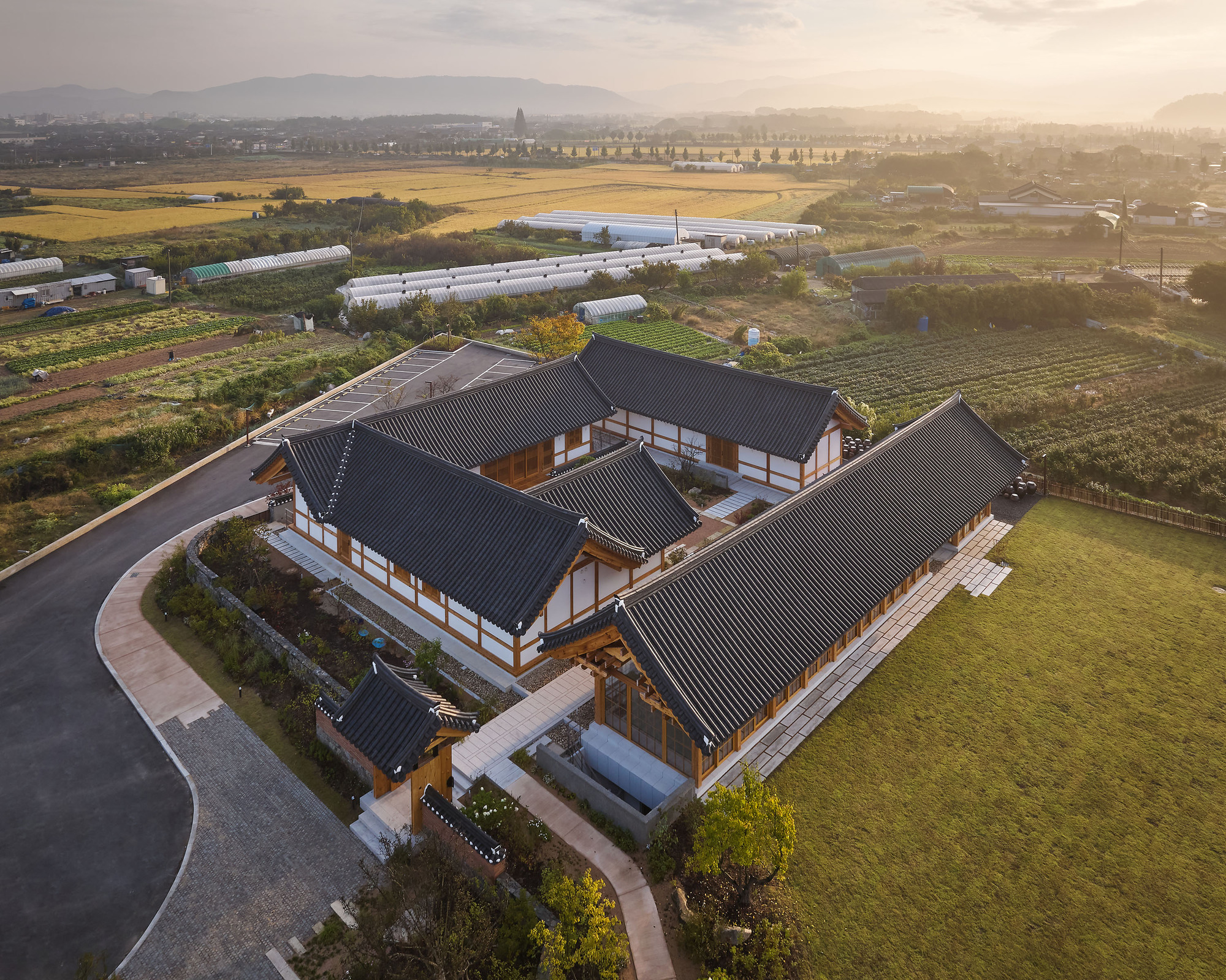 Drone view of the compound surrounded by agricultural fields and greenhouses at golden hour