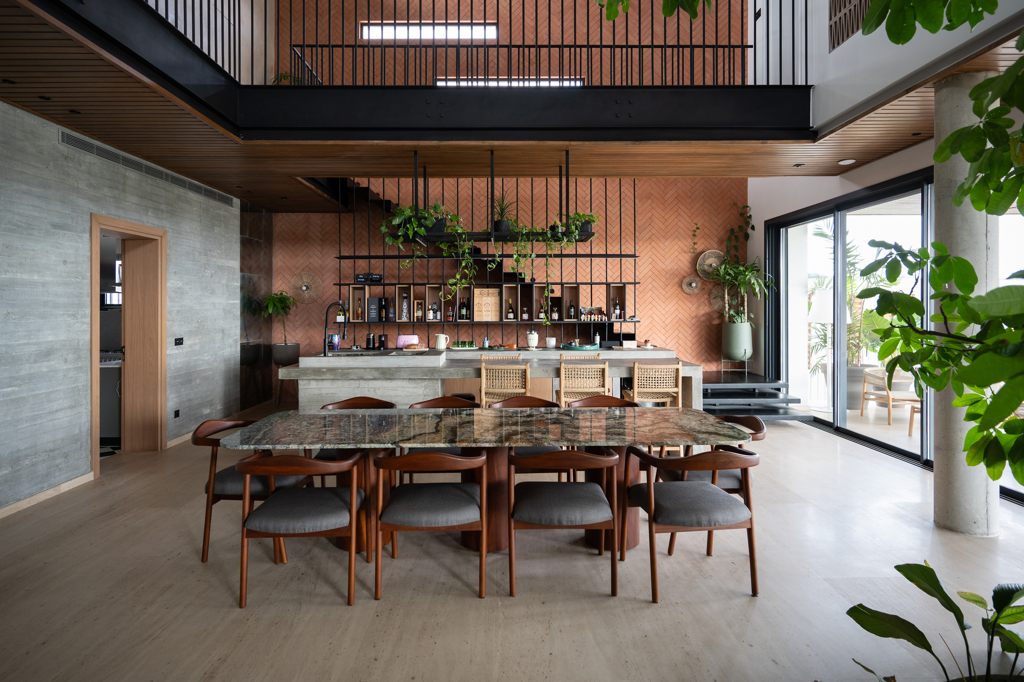 Dining area with timber table beneath black steel mezzanine and herringbone brick accent wall