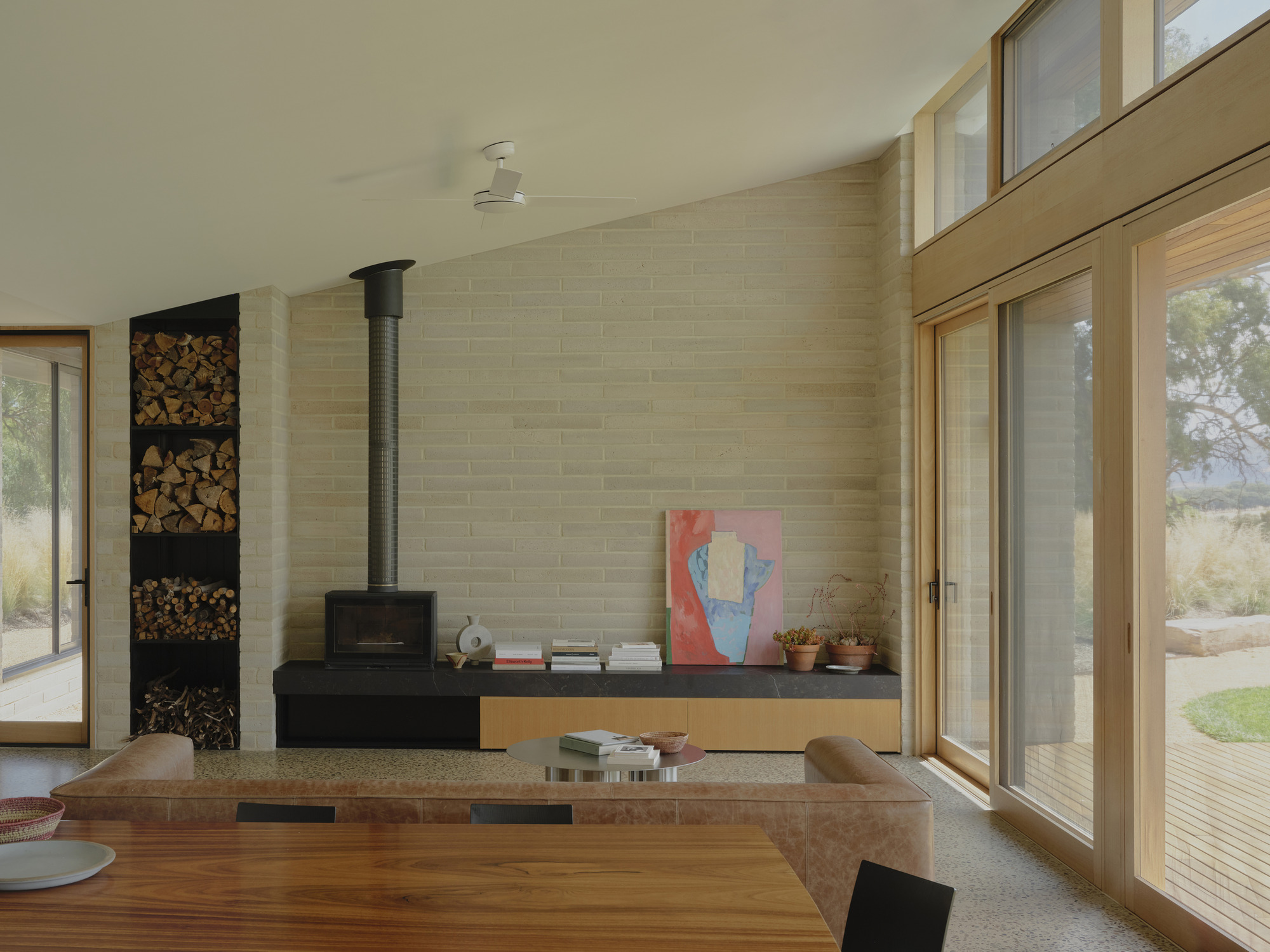 Living space with black wood stove and stacked firewood niche against a masonry block wall