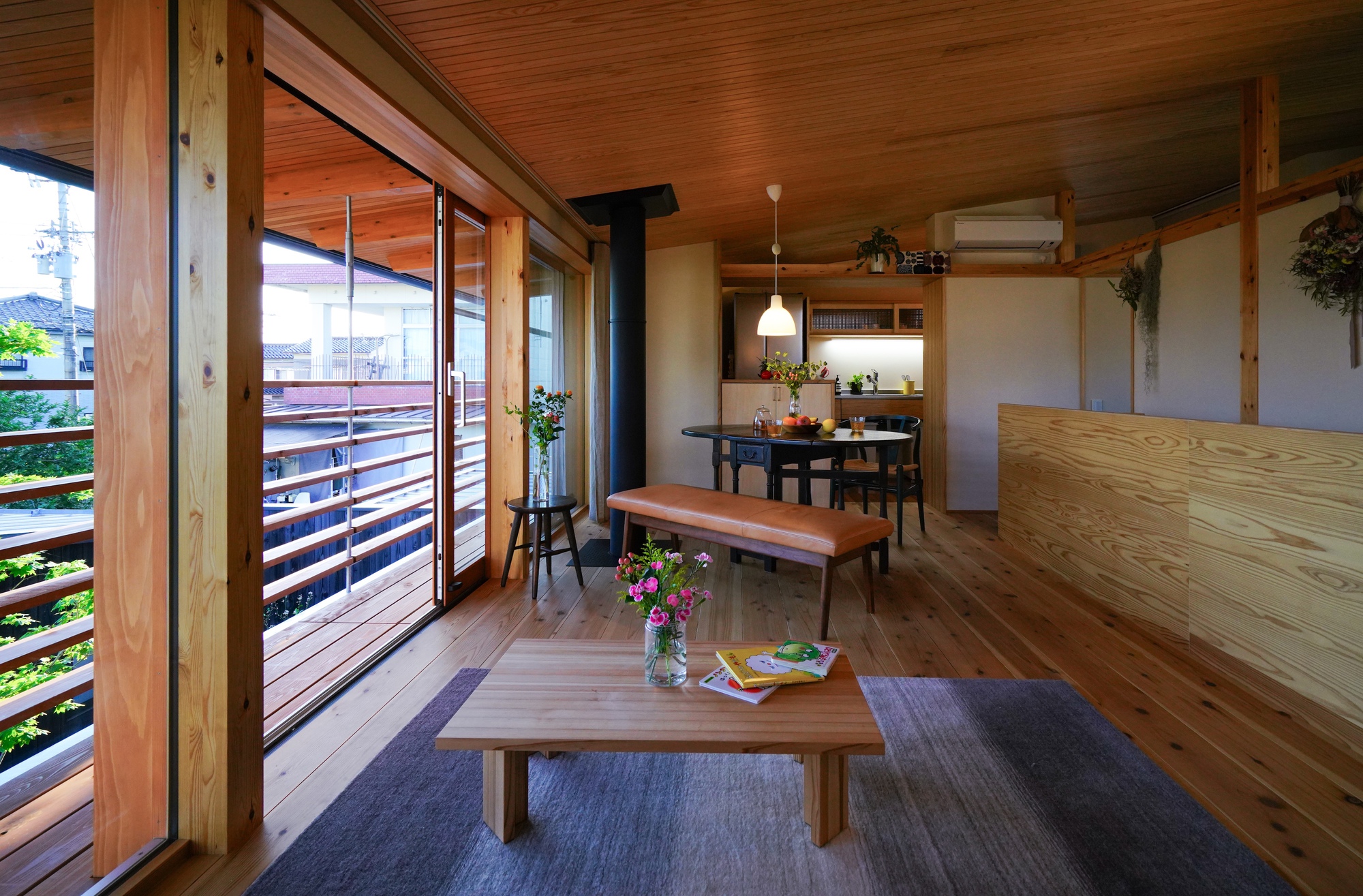Open living and dining space with exposed timber ceiling and horizontal slatted shutters