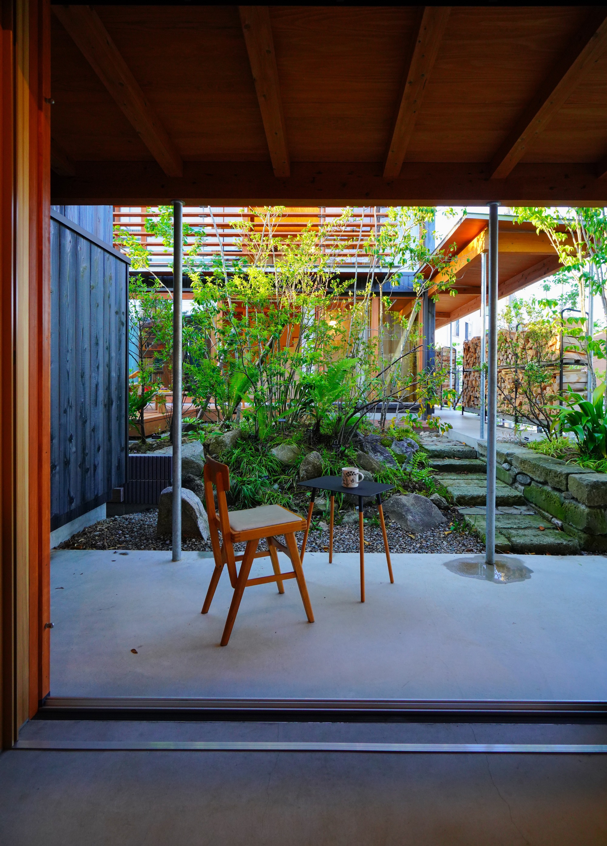 View from interior through sliding glass doors to courtyard garden with charred timber wall and horizontal screens