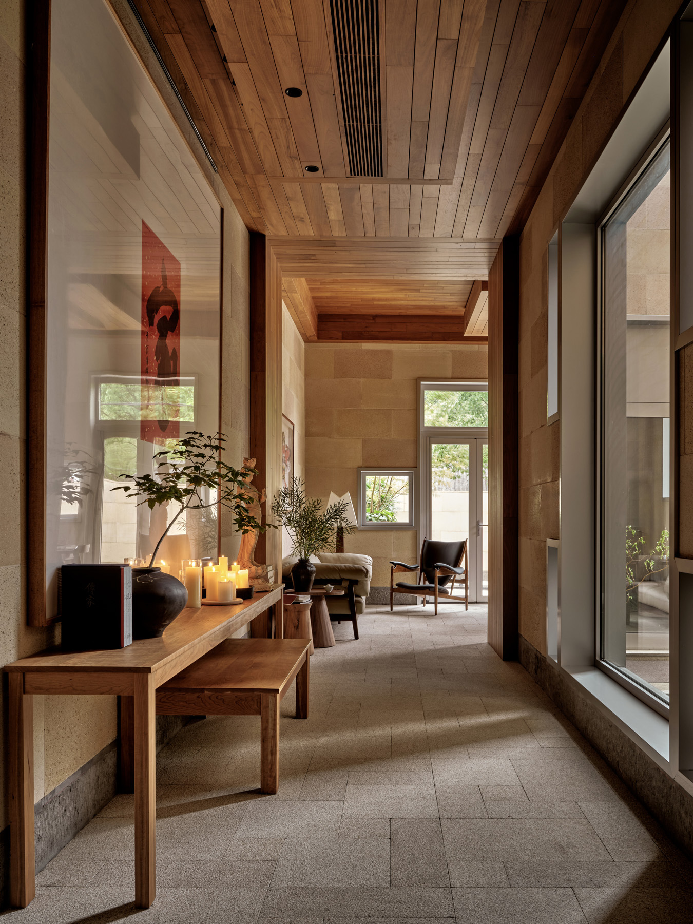 Entry hallway with timber ceiling and stone walls leading toward seating area under natural light