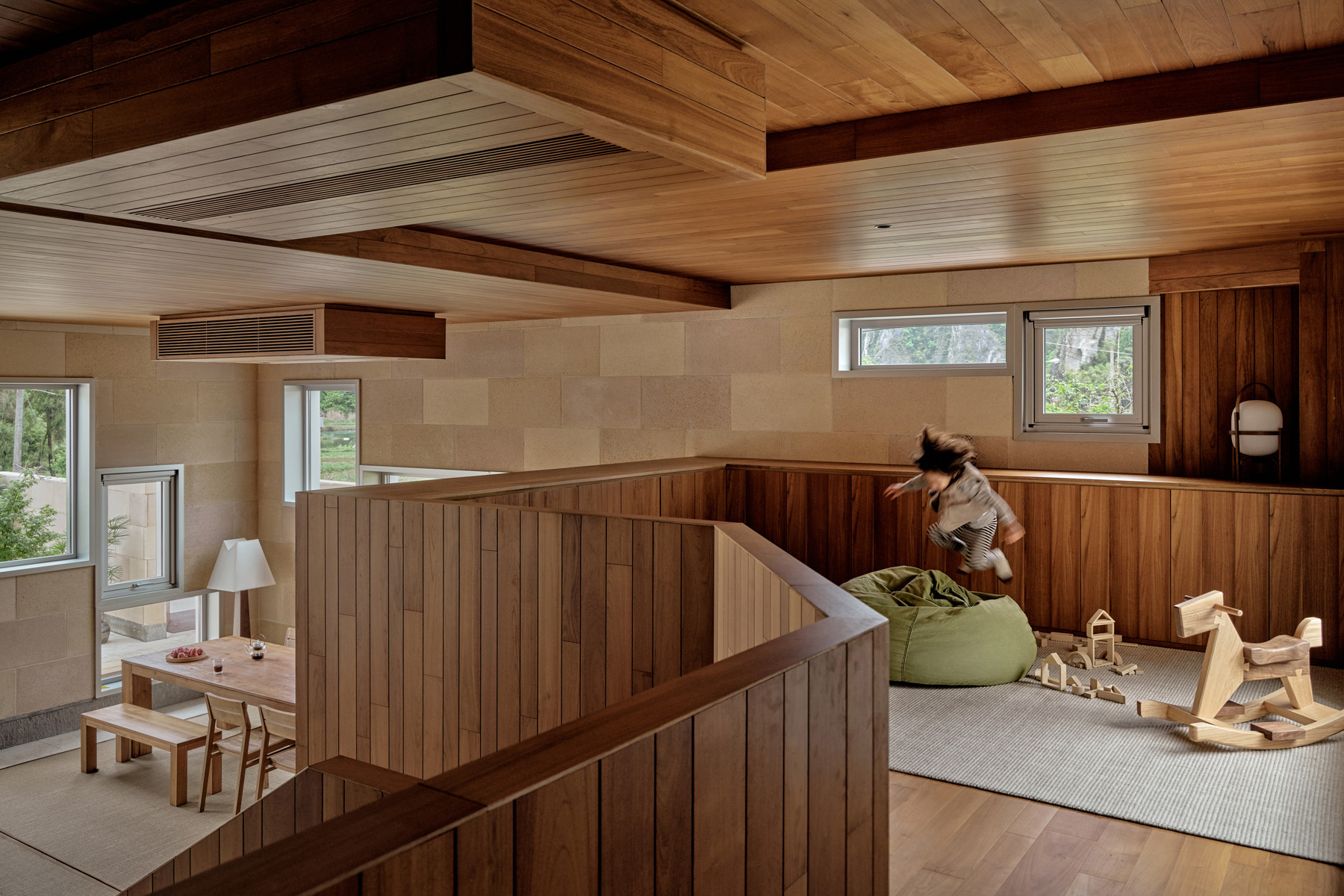 Upper level play area with vertical wood paneling and stairwell railing in afternoon sun