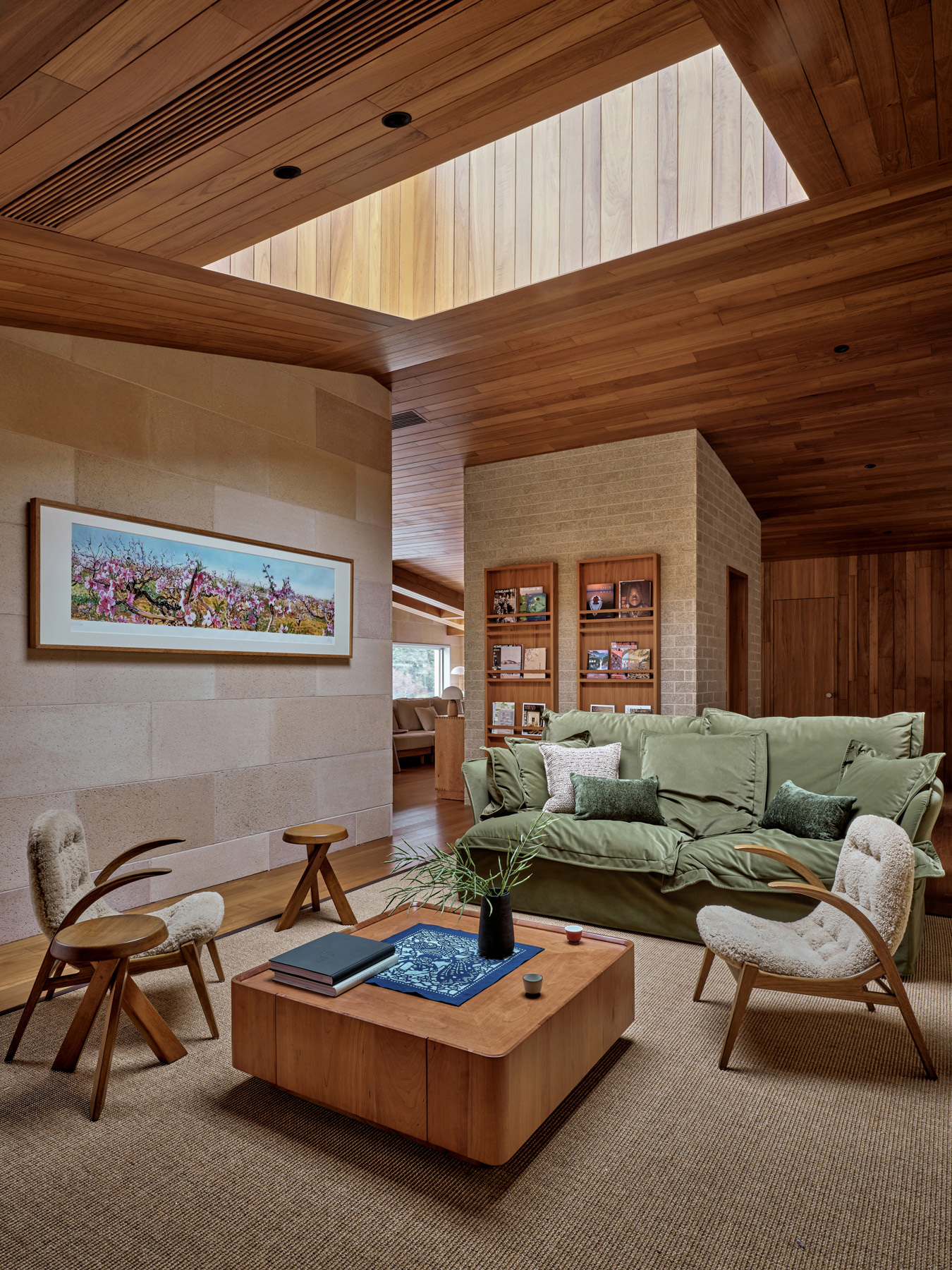 Living room with timber-lined ceiling and skylight above stone walls and furnishings