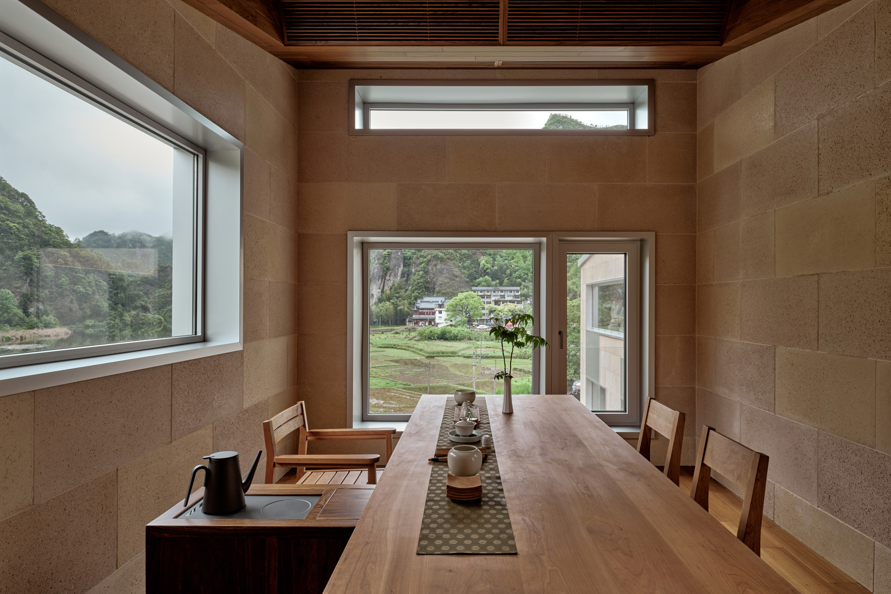 Dining room with layered clerestory windows and sandstone block walls under a timber slat ceiling