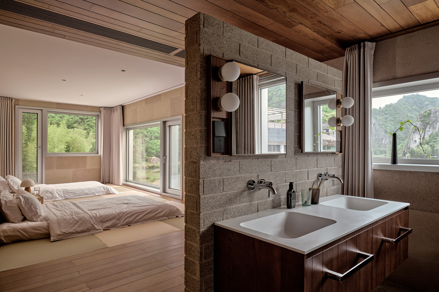 Bedroom suite with exposed timber ceiling, concrete block partition and integrated double vanity near sleeping area
