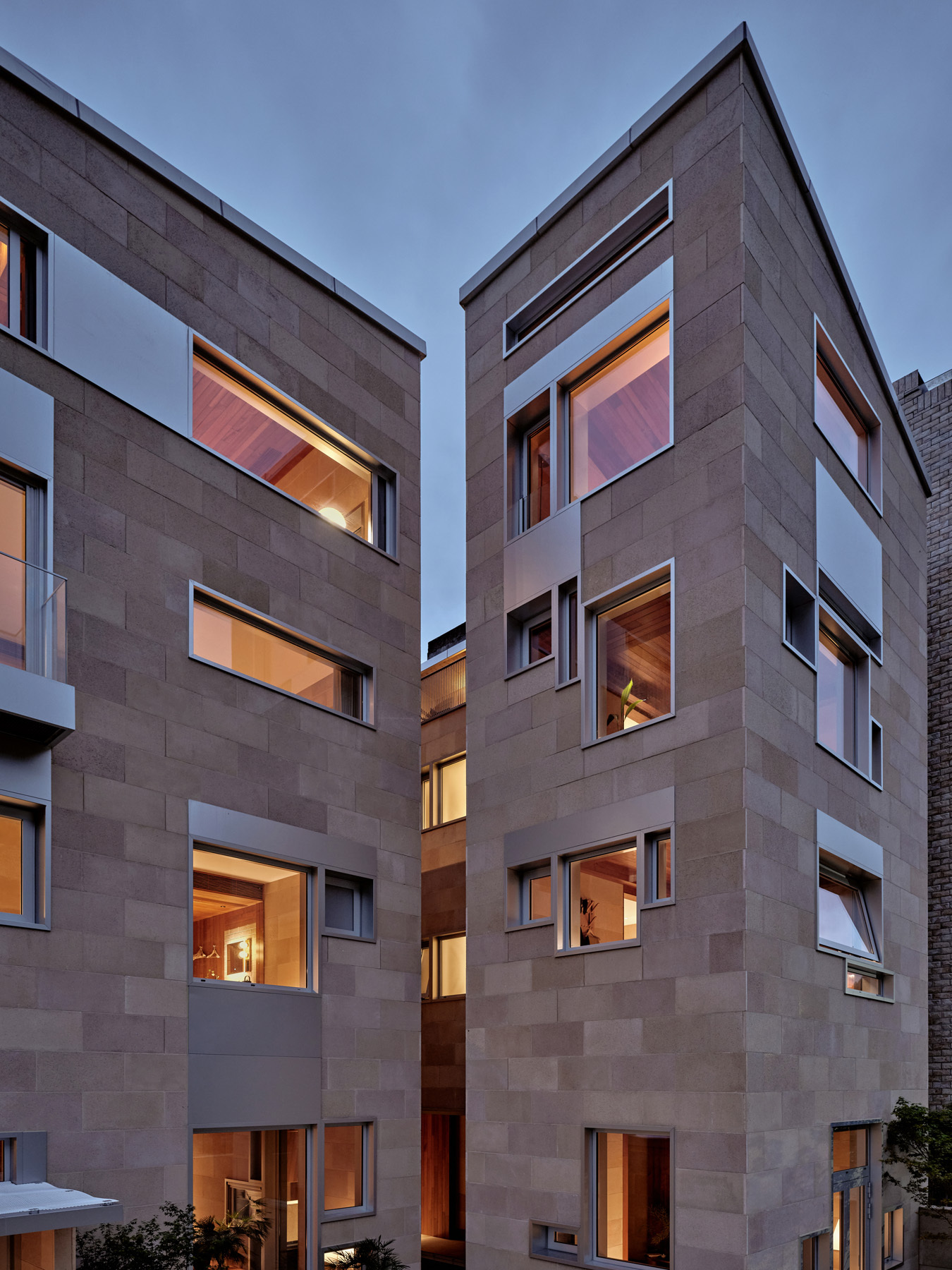 Interlocking concrete block facades with rectangular window openings illuminated at dusk