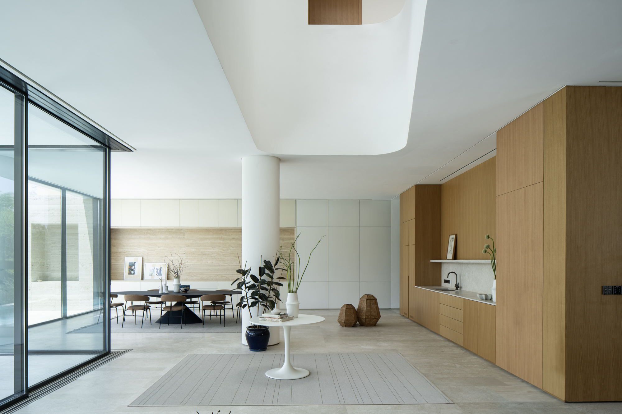 Open living space with curved ceiling cutout and oak cabinetry along one wall