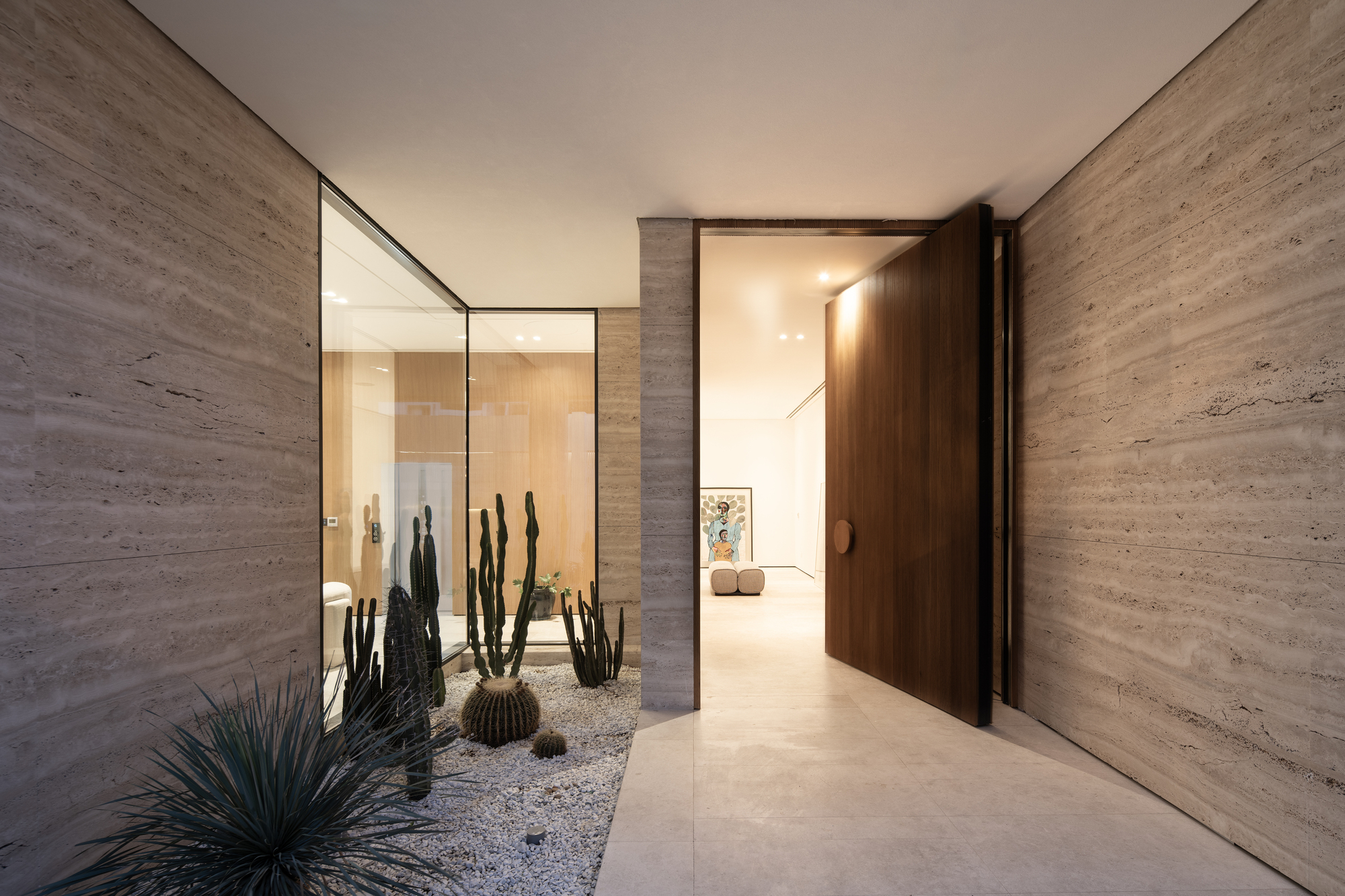 Entry vestibule with pivoting timber door and internal courtyard planted with cacti and agave in gravel
