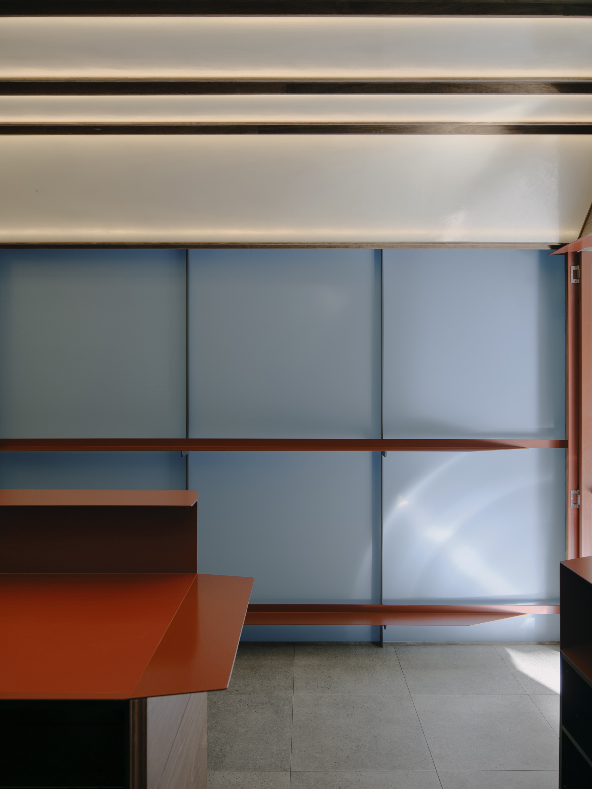 Interior view of the translucent sliding screens with red metal shelving in filtered daylight